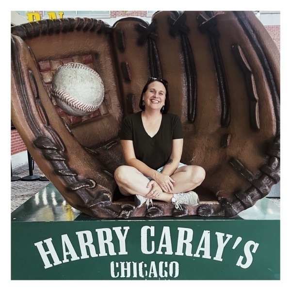 Liz sits in a giant baseball glove.