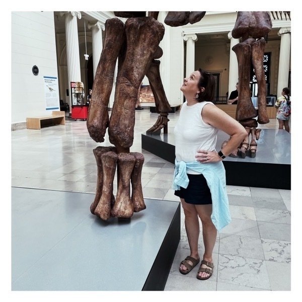 Liz poses by the leg of a dinosaur fossil.