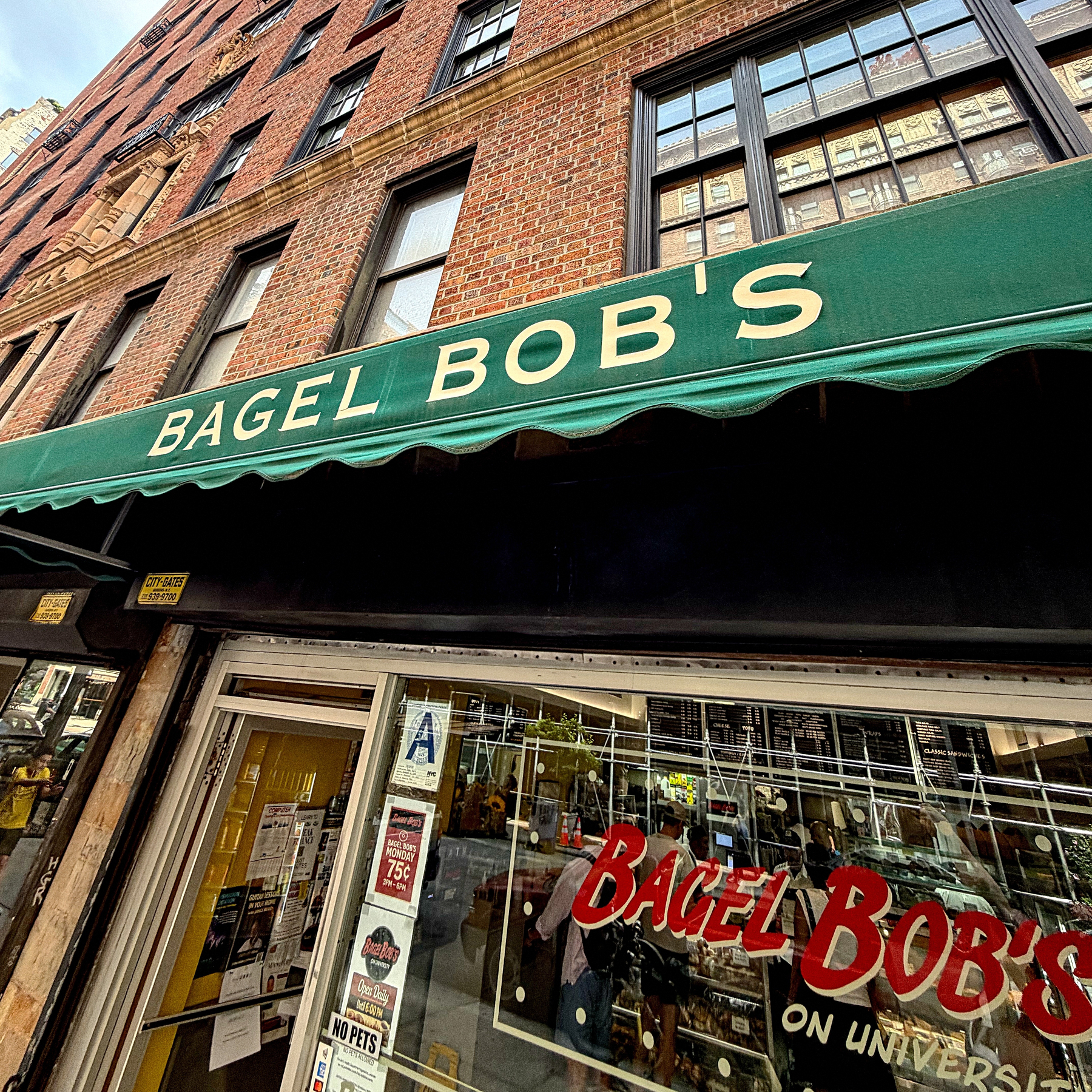A storefront with a green awning displays the name BAGEL BOB'S above a window that also has the store's name and additional text.