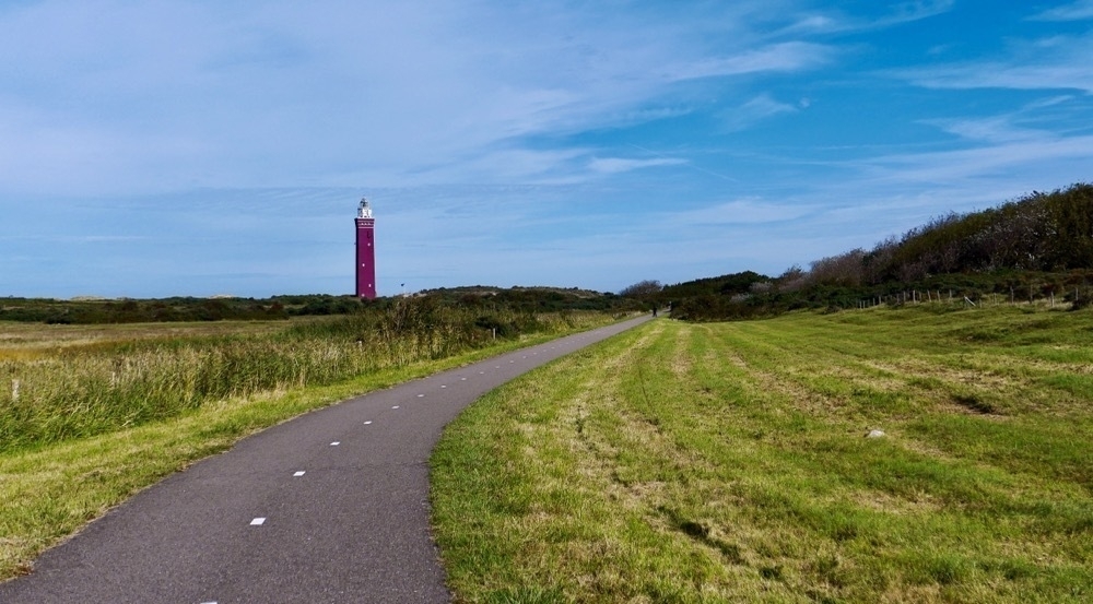 lighthouse in the dunes near Ouddorp, the path wends towards the lighthouse on the horizon, forest to the right