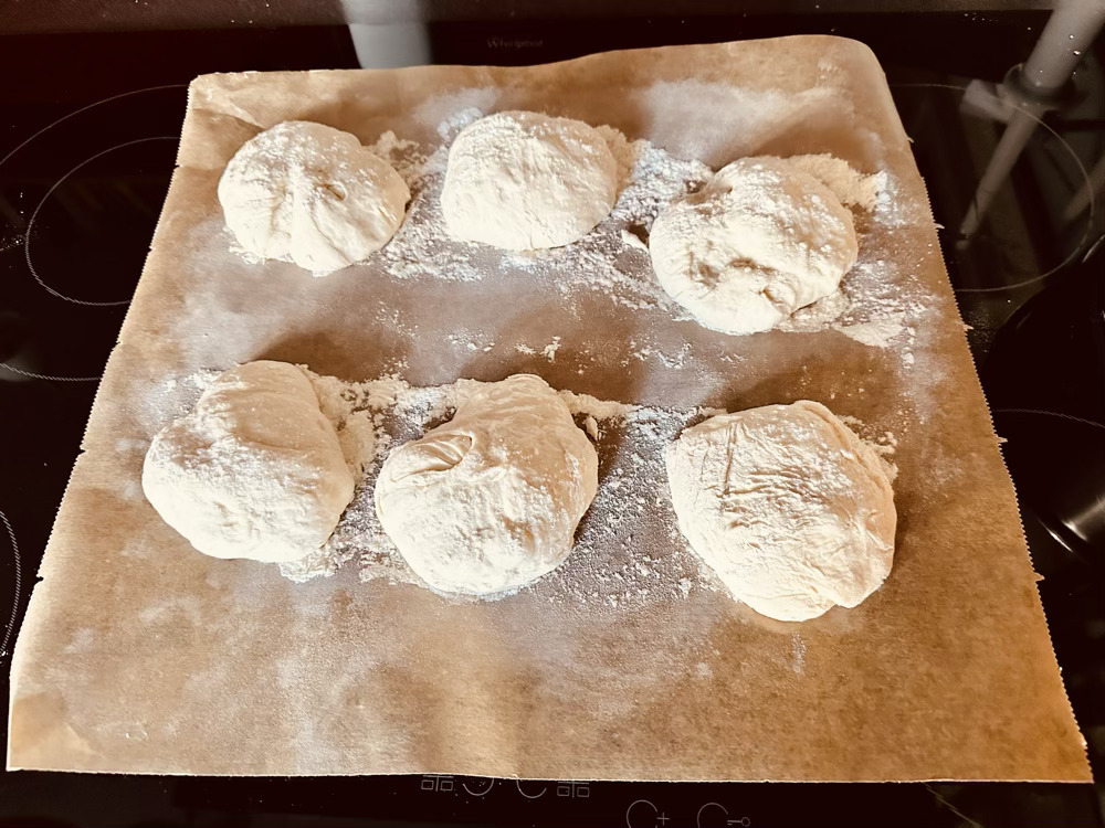 6 roughly shaped bread roll on baking parchment 