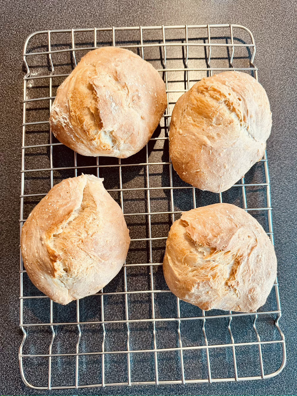 4 crusty bread rolls on the cooling rack. Fairly irregular. 