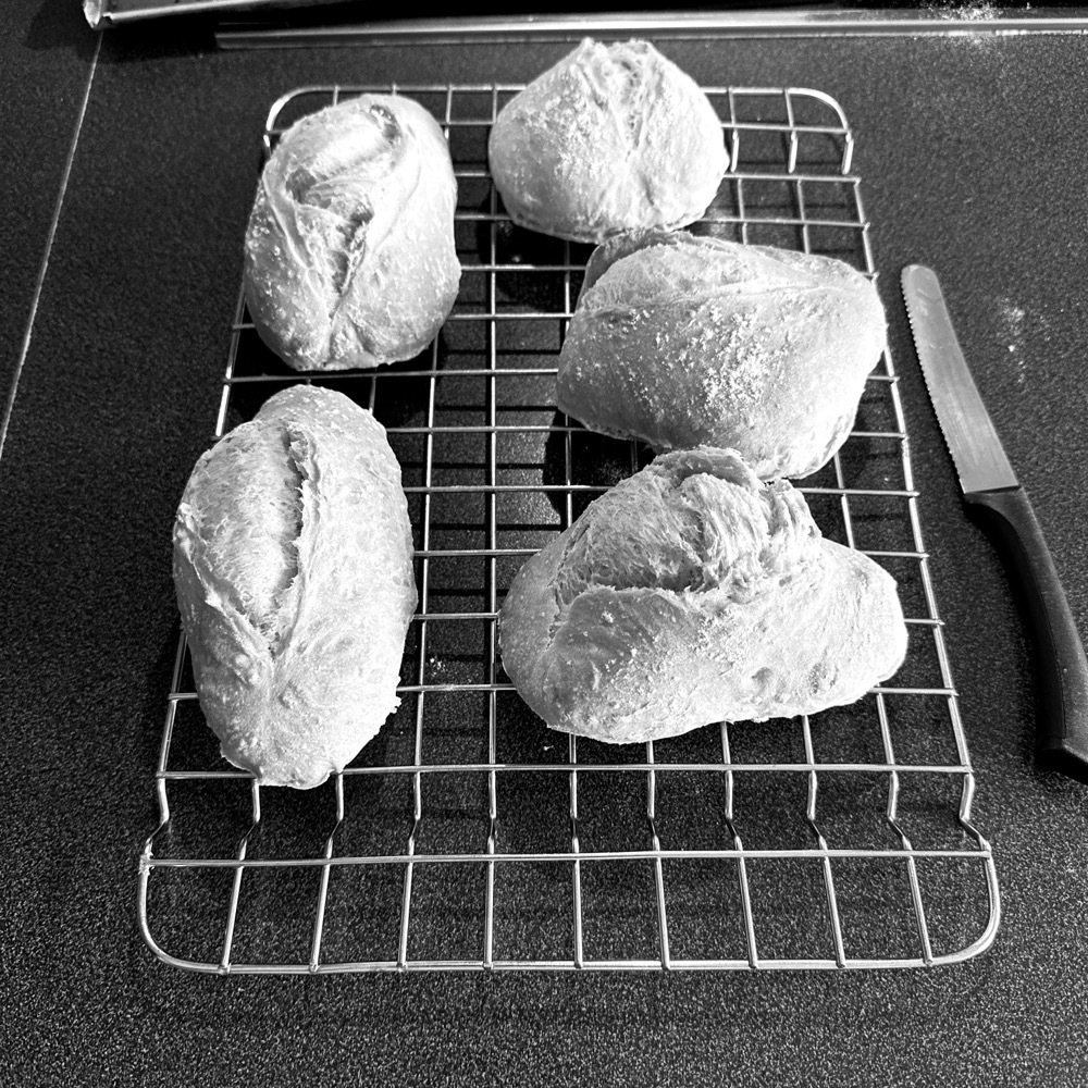 b/w picture, 5 rolls on the cooling rack, small bread knife to the right of the rack