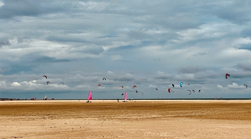 beach, dramatic sky, kite surfing in the background 