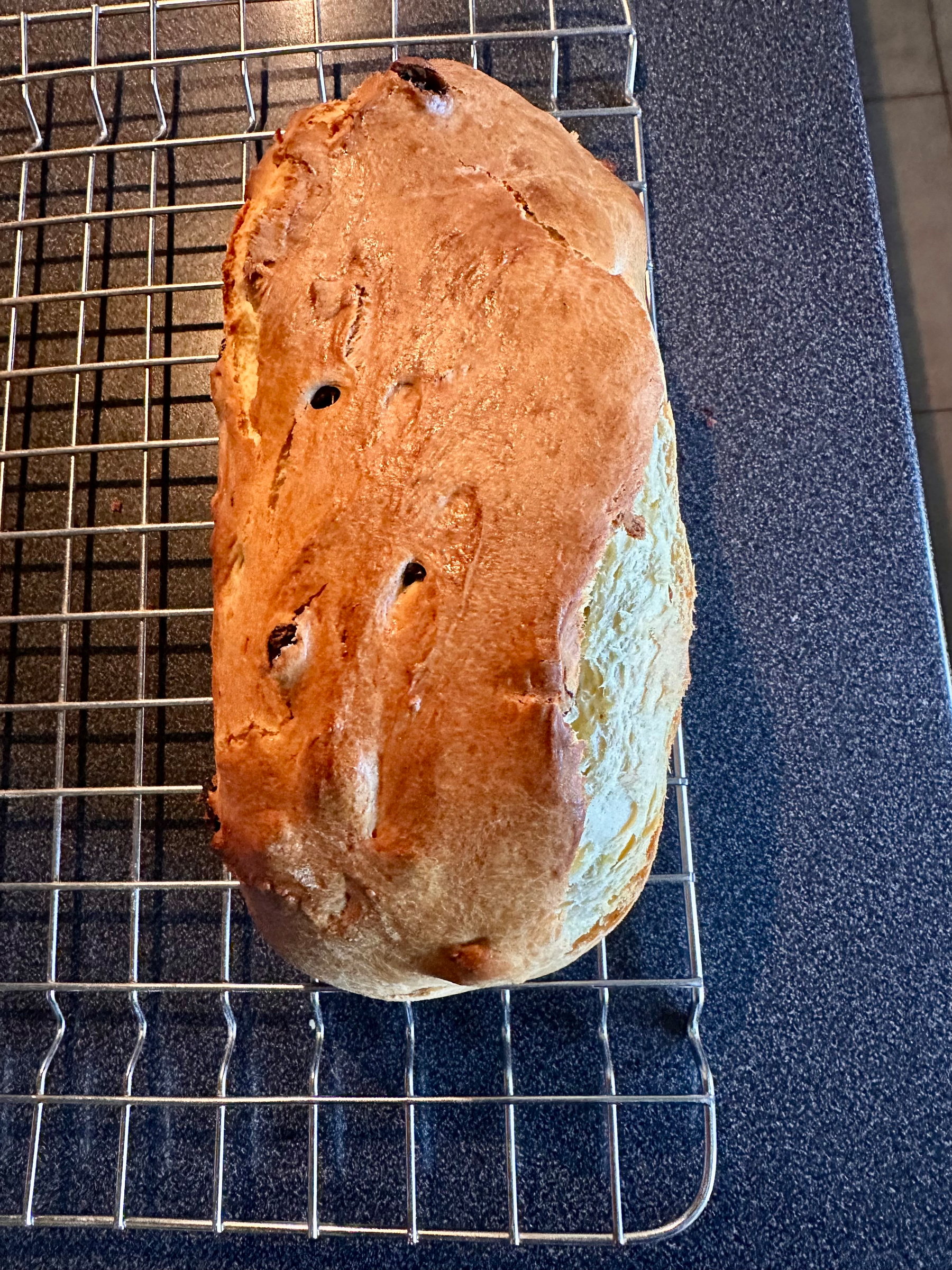 A loaf of freshly baked brioche with a golden-brown crust rests on a cooling rack.