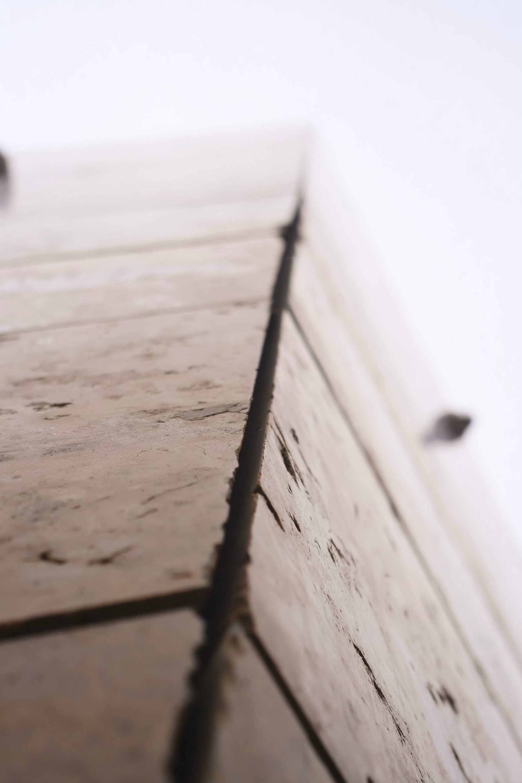 A close-up view of the corner of a stone or concrete wall with visible texture and gaps between the blocks.