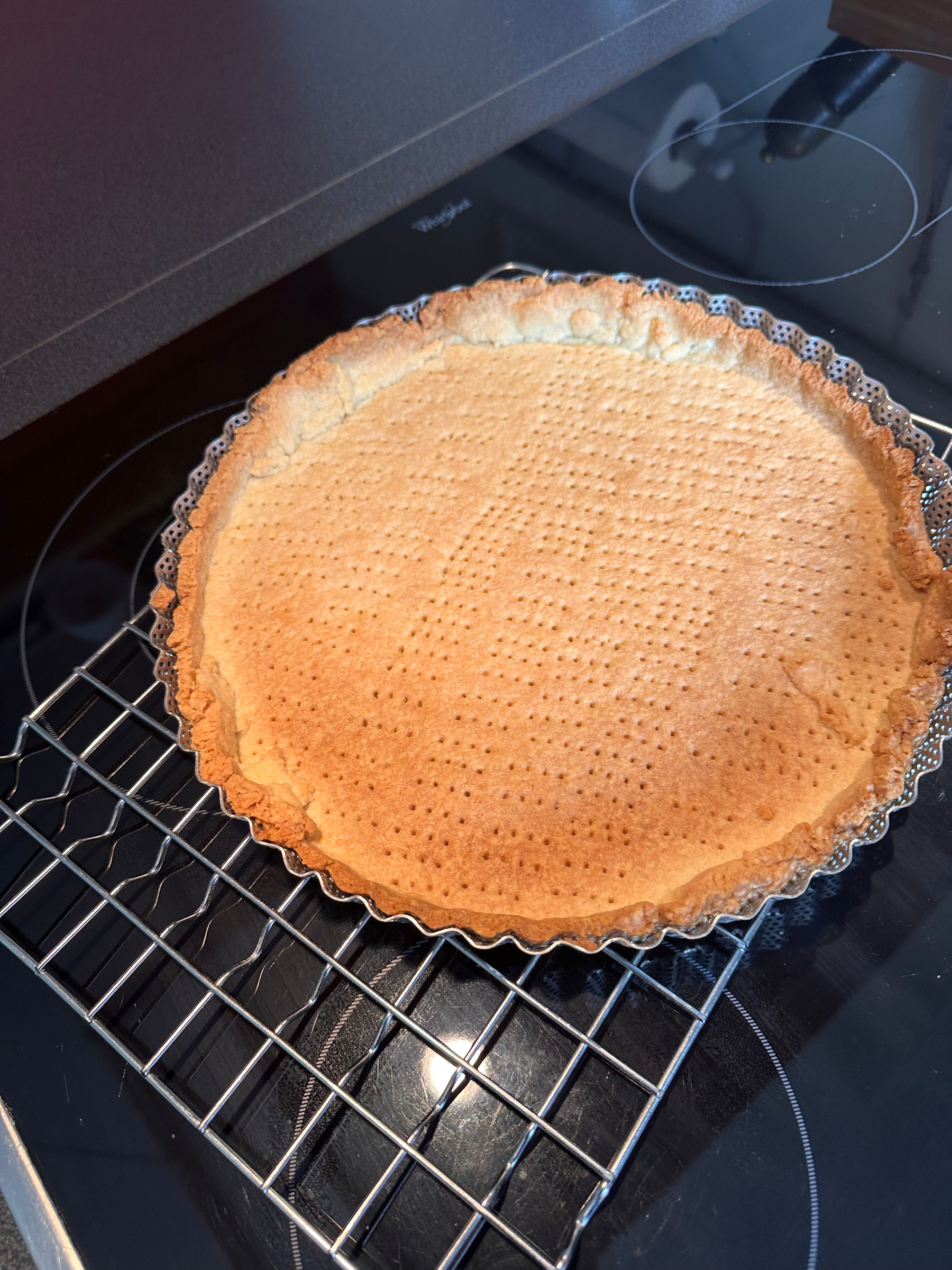 A baked pie crust rests on a cooling rack.