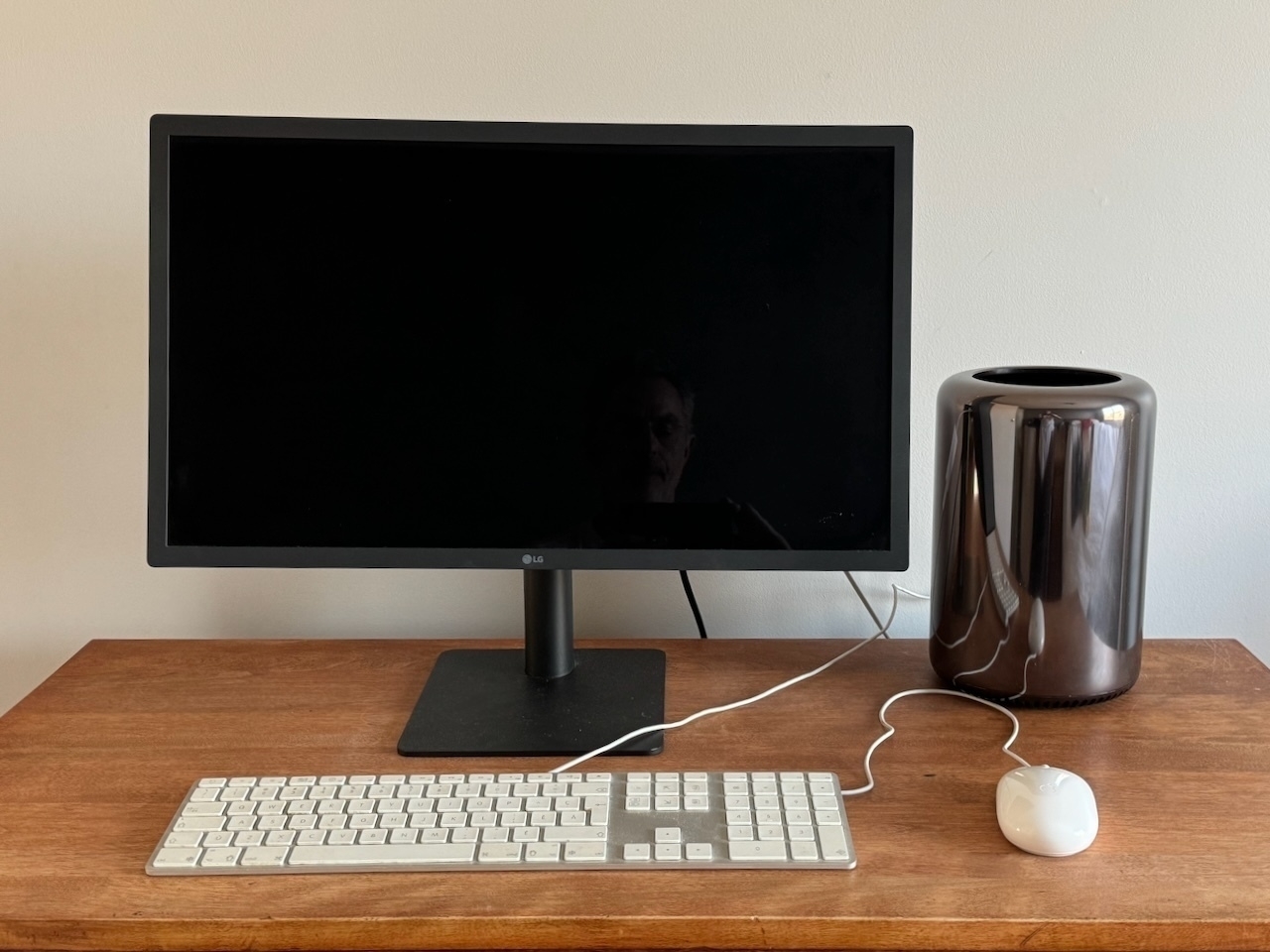 Auto-generated description: A computer setup with a black monitor, white keyboard, and mouse on a desk next to a brown speaker.