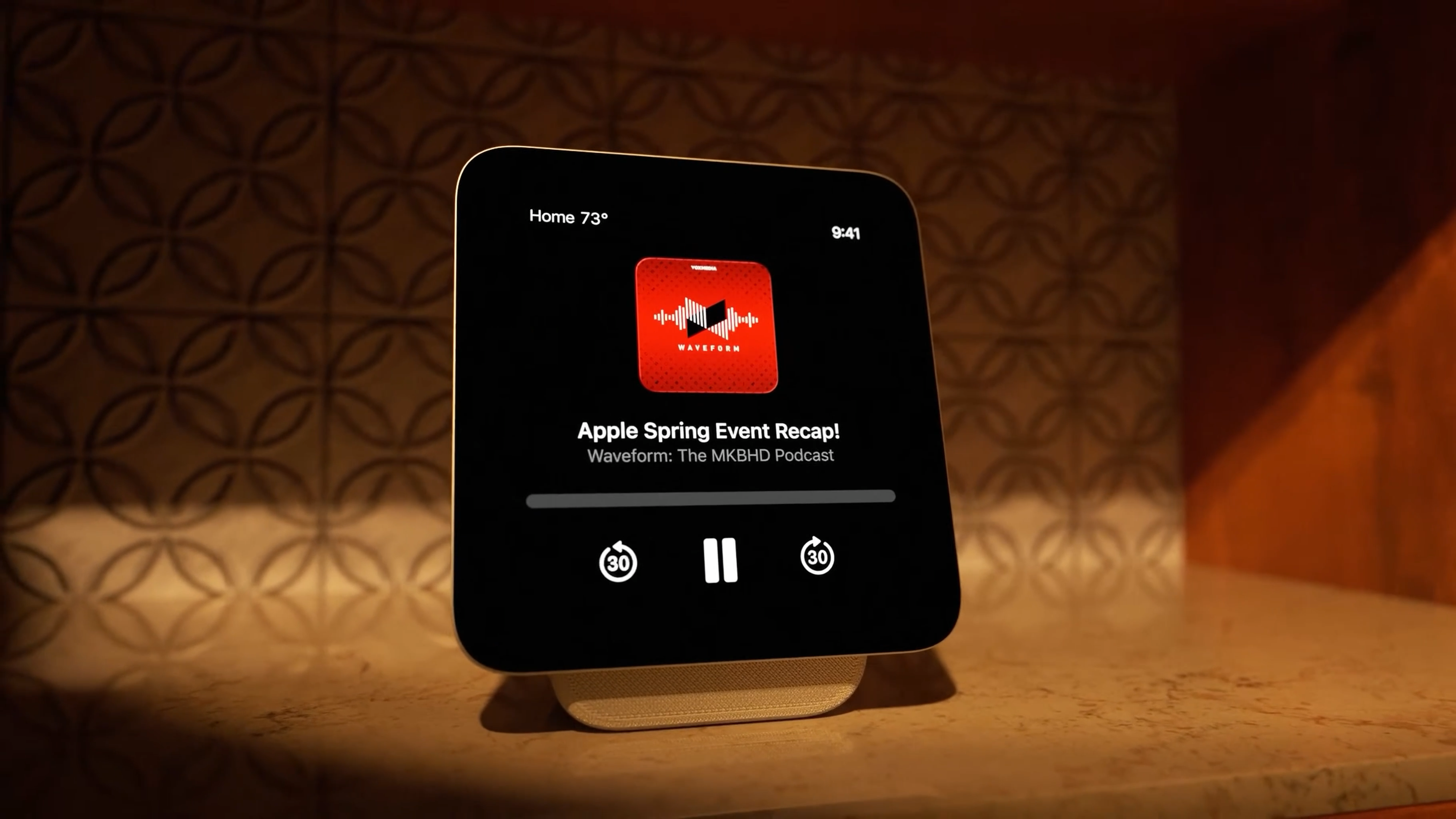 Auto-generated description: A smart display device showing a podcast playback screen titled Apple Spring Event Recap! from the Waveform: The MKBHD Podcast.