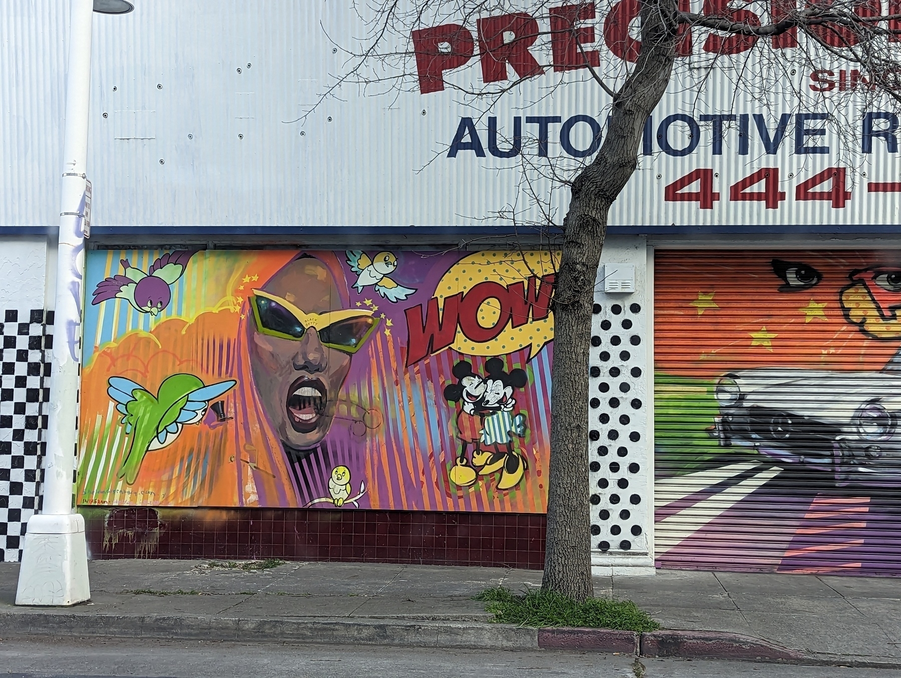 A mural outside an auto repair business Wednesday, March 23, 2023 along Broadway Auto Row in Oakland, California depicts a blue green hummingbird, an African American woman who looks a little bit like Grace Jones wearing sunglasses, a bowdlerized version of Mickey and Minnie Mouse and a tiny hand drawn owl.