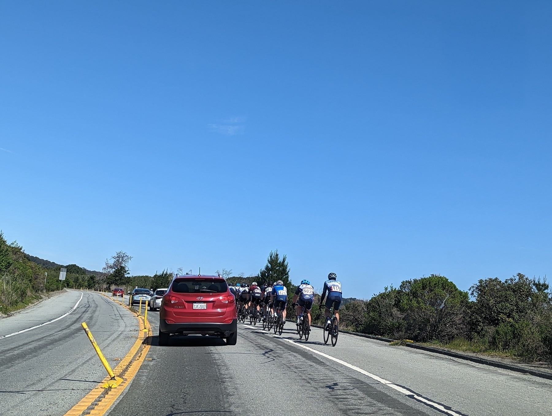 A peloton of road bicyclists rides in the bike lane alongside light traffic in  northbound San Pablo Dam Road west of the the San Pablo Reservoir under blue skies Saturday, April 29, 2023 in unincorporated Contra Costa County
