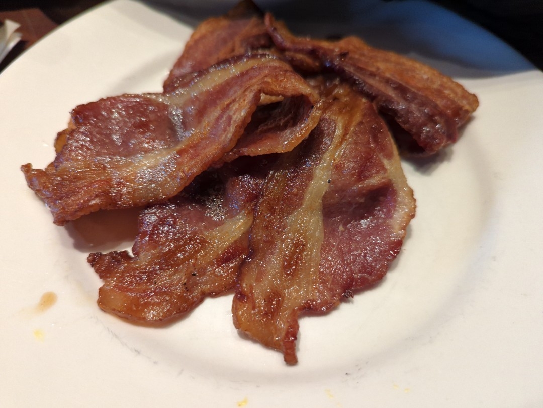 Several strips of hard fried bacon sit folded on a white plate at Rooz Cafe in the 1900 block of Park Boulevard on Sunday, April 16th 2023 in Oakland, California.