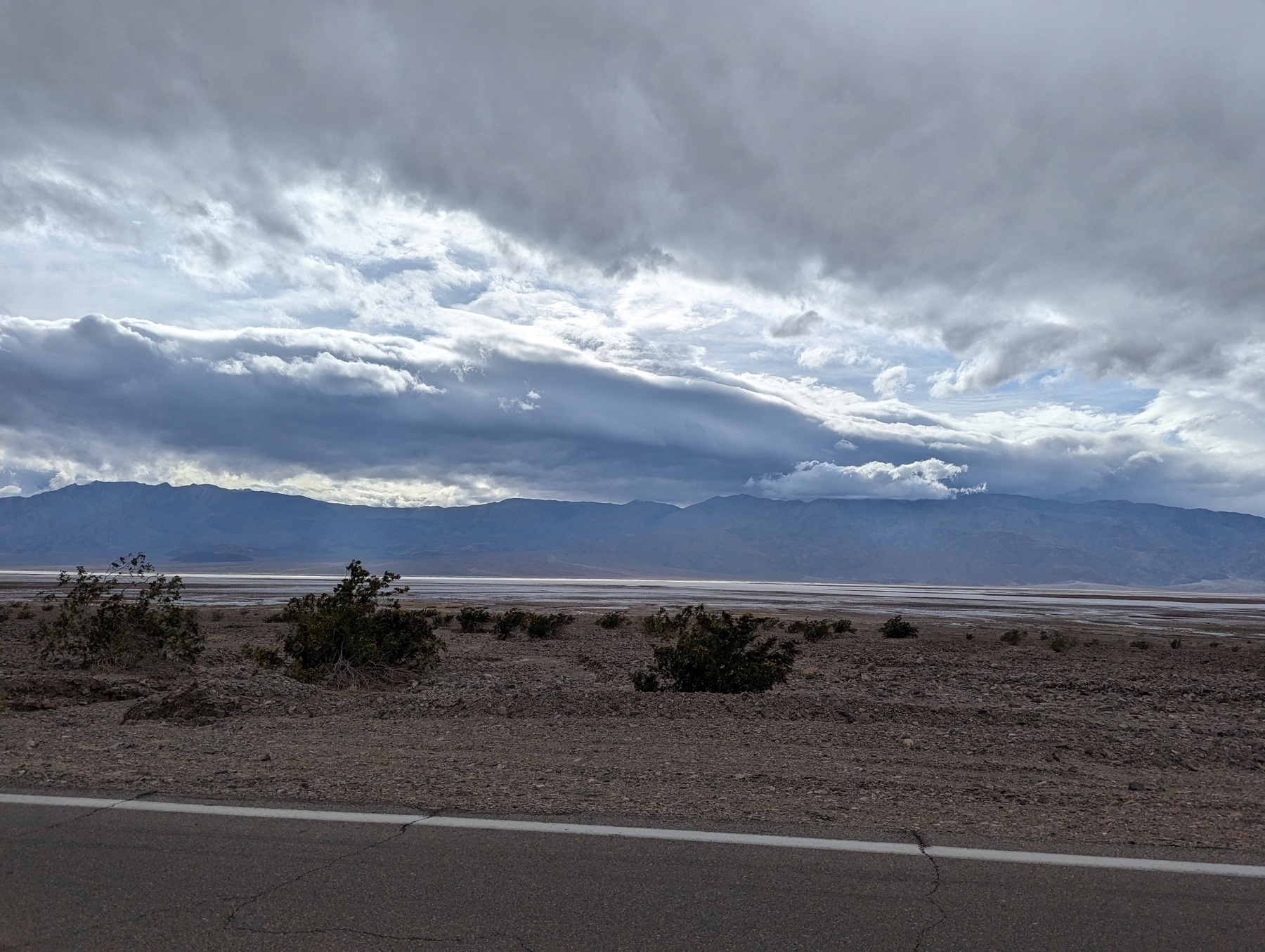 A roughly southern view of clouds, mountains and brush Tuesday, March 14, 2023 along eastbound Highway 190 lanes in Death Valley National Park between Stovepipe Wells and Furnace Creek.