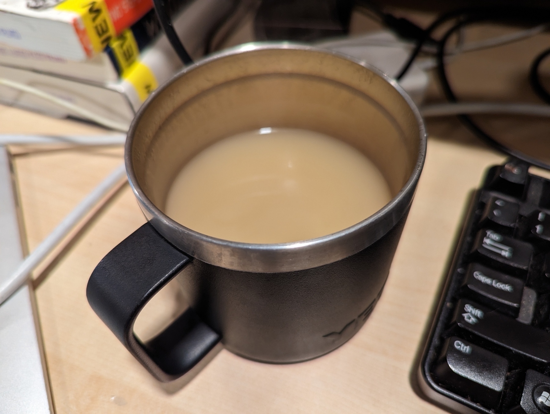A small metal cup full of organic chicken bone broth sitting on a blond wood desk Wednesday, March 22, 2023 in San Pablo, California. 