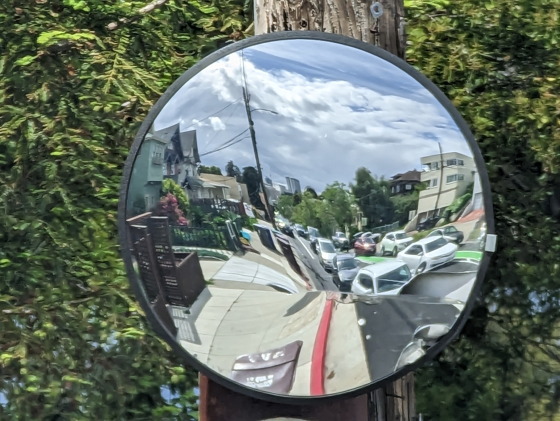 A circular shaped mirror reflecting lanes of northbound Harrison Street traffic south of Interstate 580 is mounted on a wooden telephone pole Tuesday, May 2, 2023 in Oakland, California.
