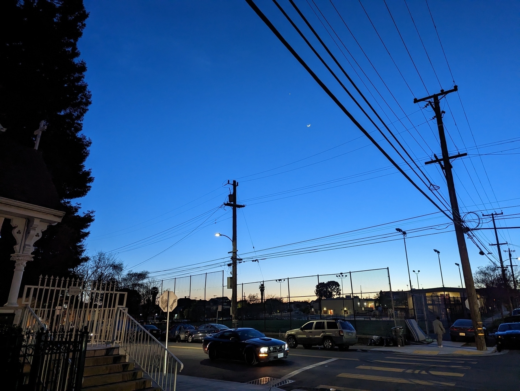 A view of deep blue 8 pm evening sky from near 23rd Avenue and Foothill Boulevard in Oakland, California on Saturday, April 22, 2023 next to an athletic field surrounded by lamps and power lines.