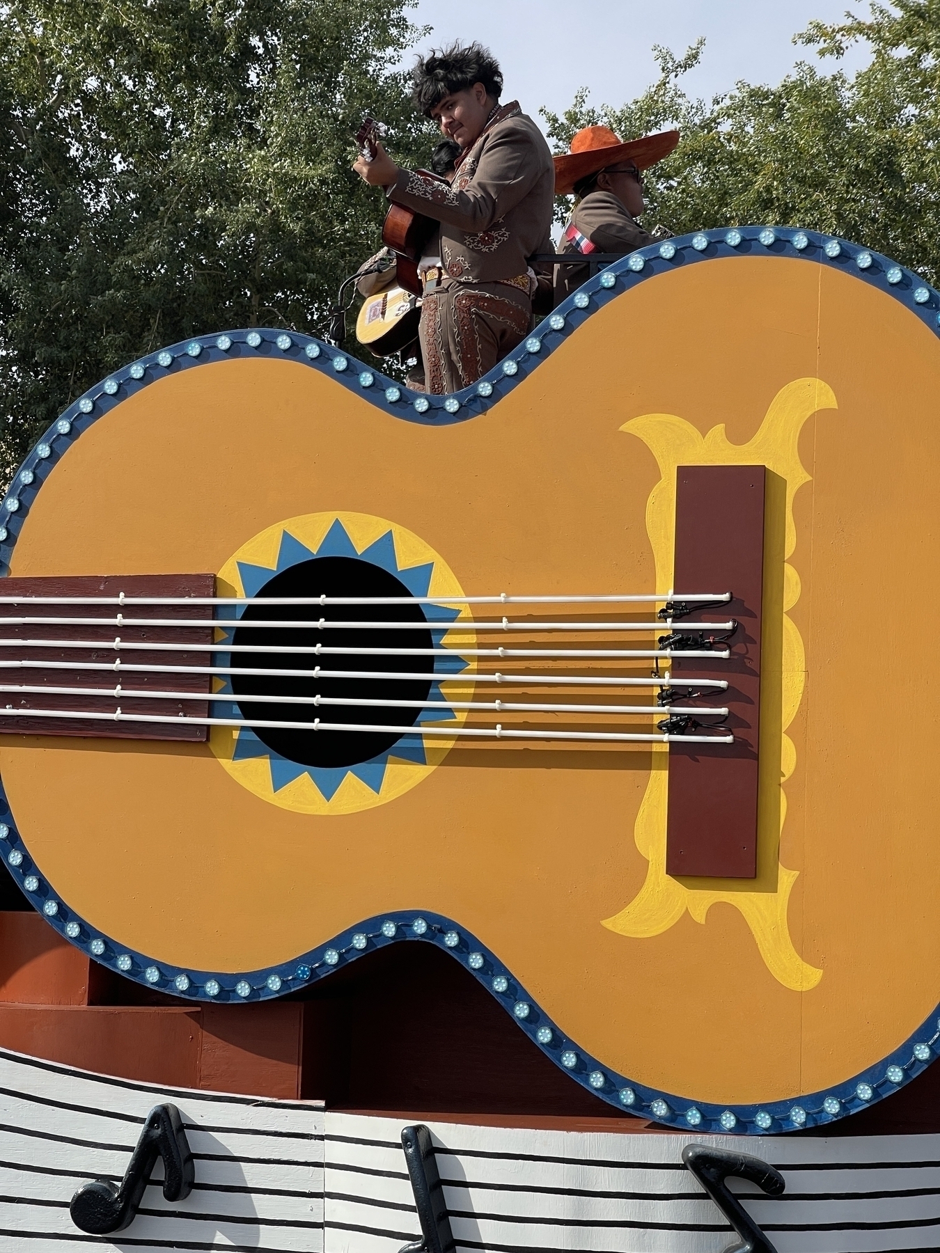 Mariachi playing a guitar on a giant guitar parade float