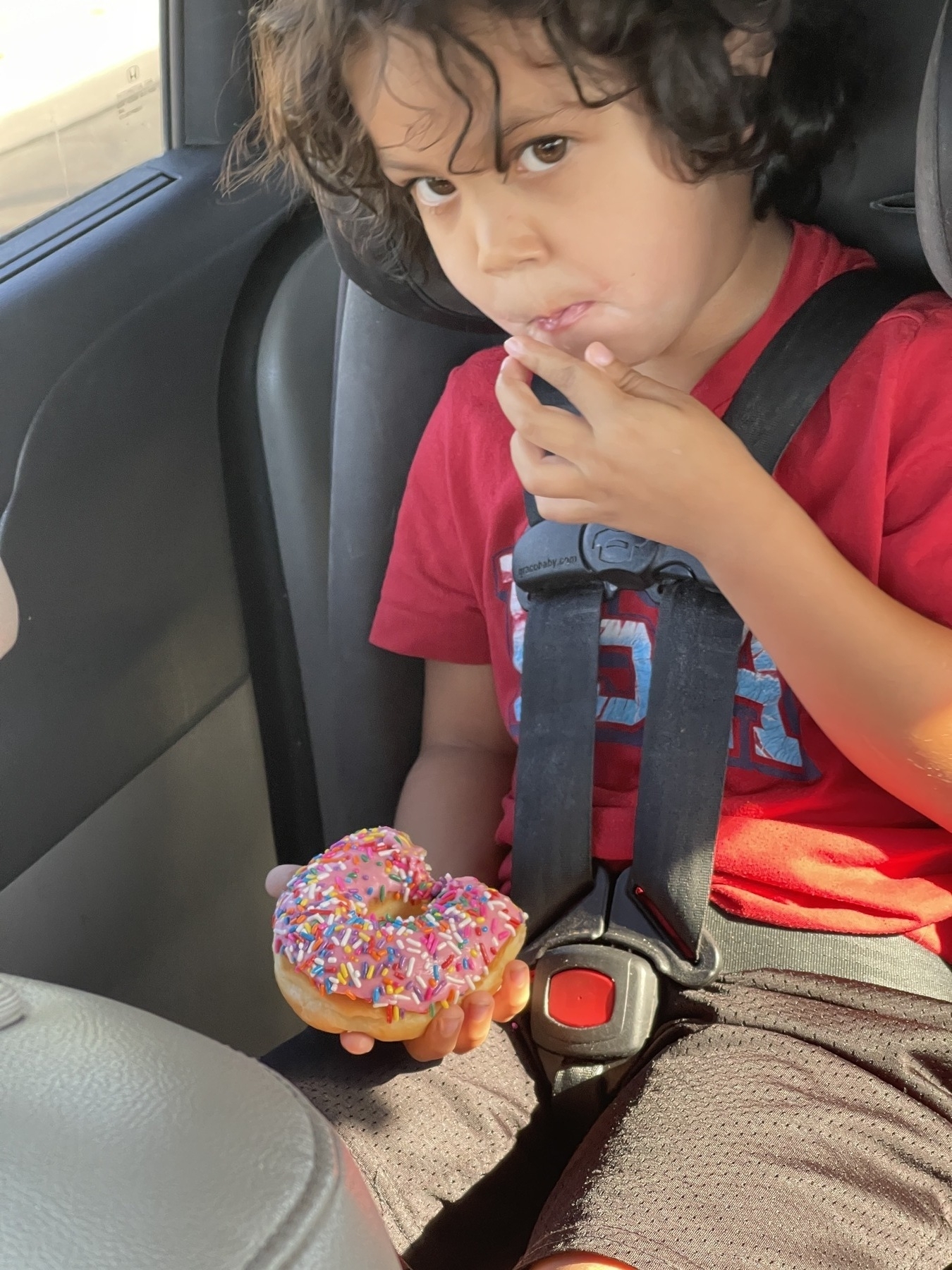 Diego eating a donut in his car seat