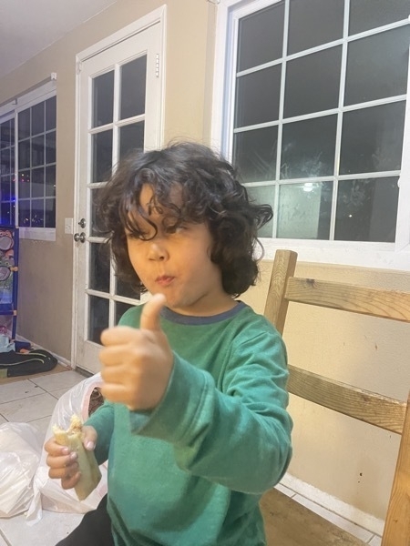 Young boy giving a thumbs up for the tamales