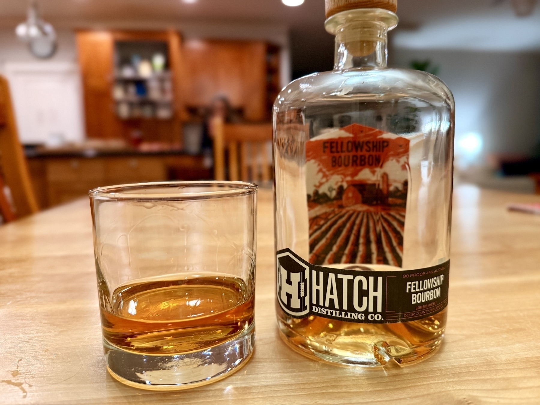 A bottle of Fellowship Bourbon from Hatch Distilling Co. beside a glass with a two-finger pour.