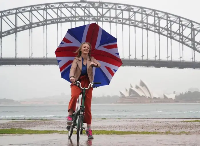 Liz Truss with a Union Jack umbrella on a bike