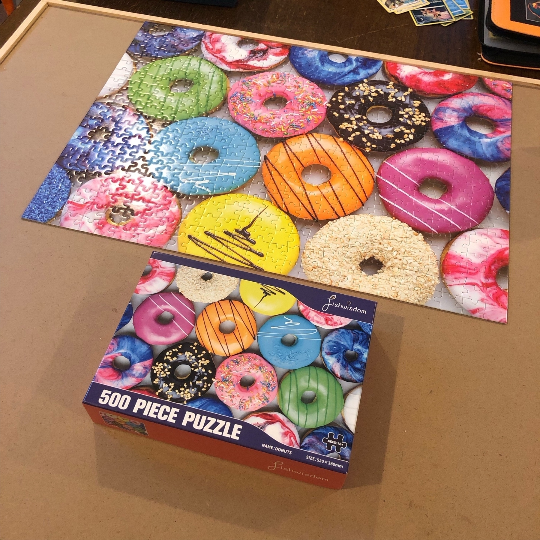 Photo of a donuts jigsaw puzzle and its box. The joke is the puzzle really doesn’t have a top or bottom—but I have the puzzle oriented opposite to the image on the box. 