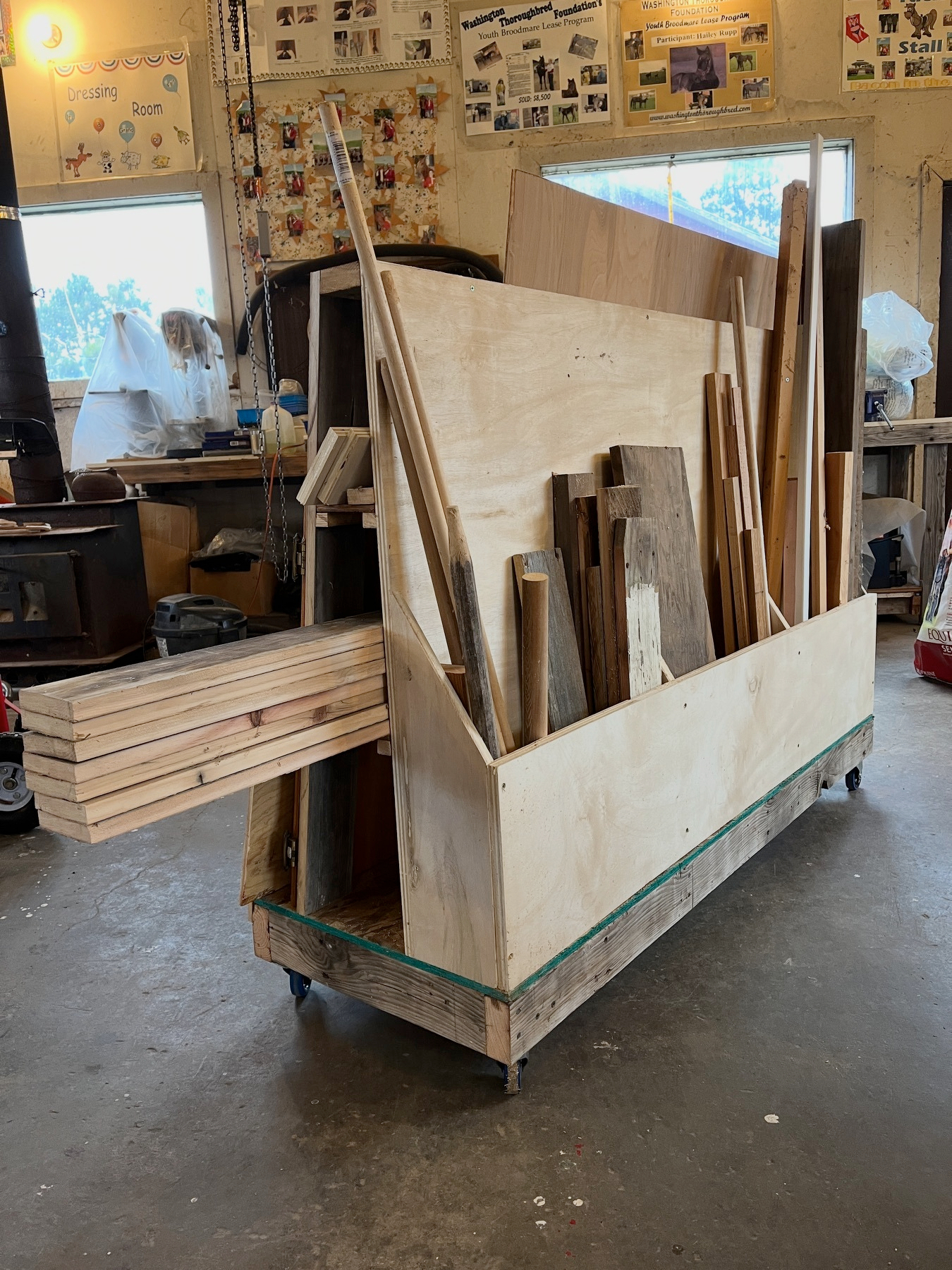 A wooden cart is filled with various sizes of wooden planks and boards in a workshop setting.