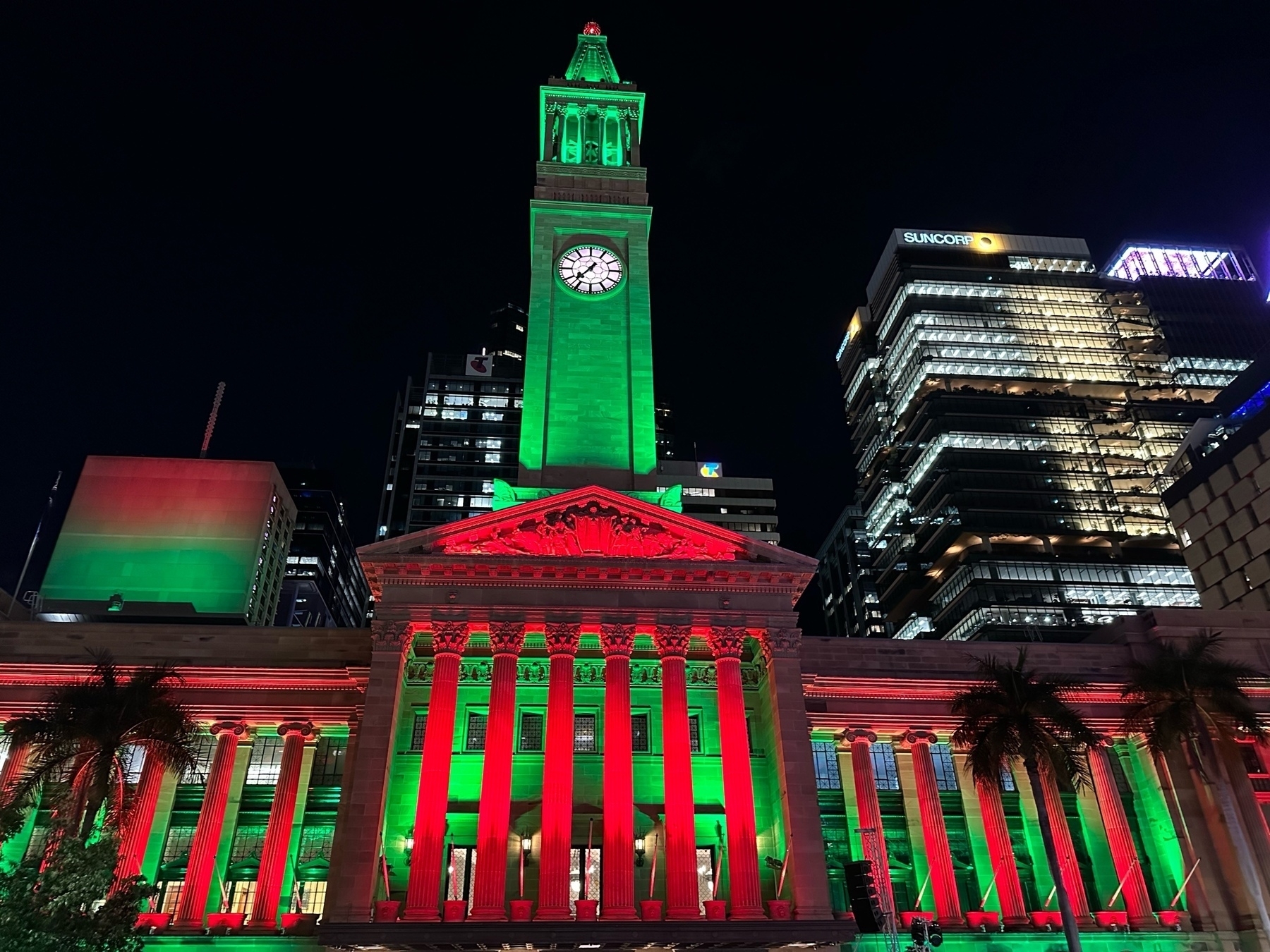 Brisbane City lit in red and green lighting. The front columns are all red with the portico behind in green. Clock tower is all green.