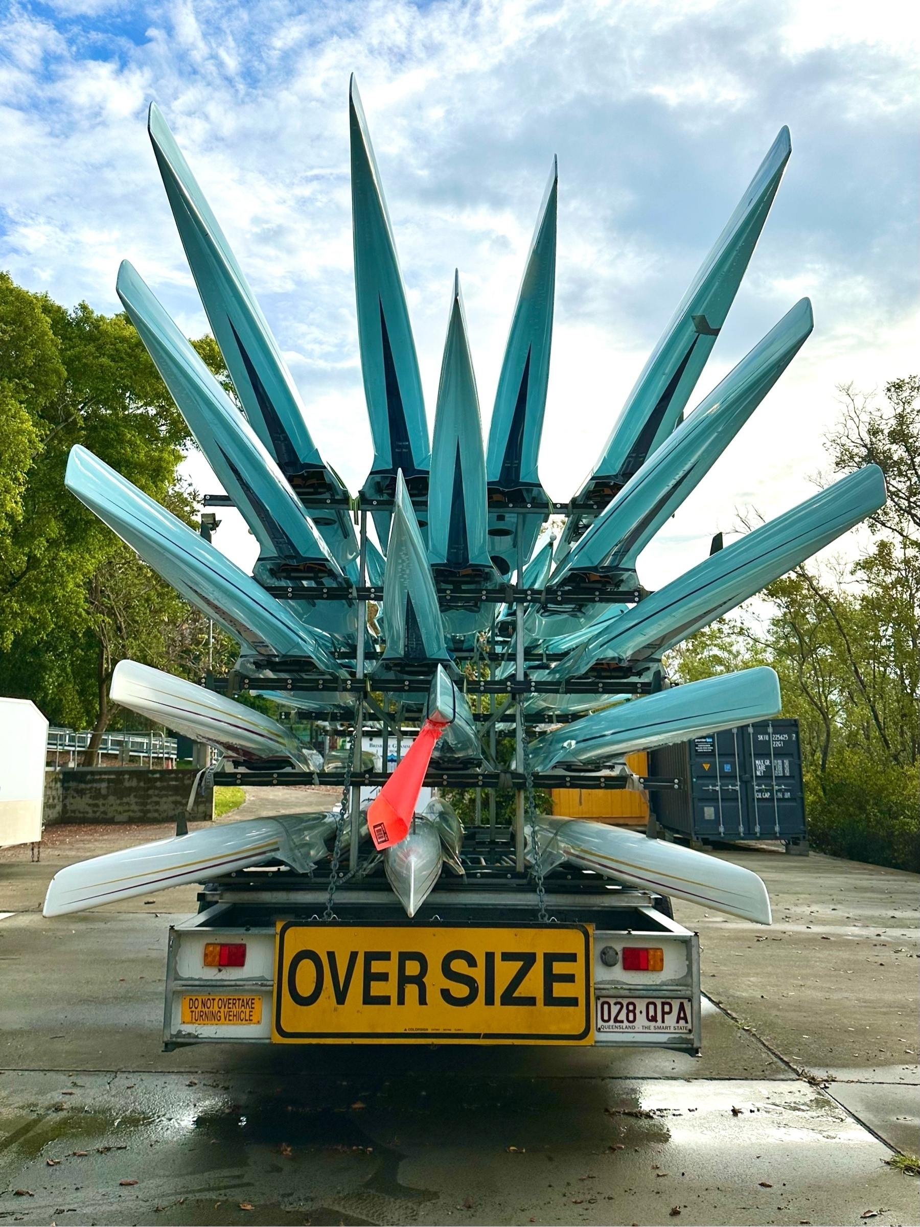 The rear of a trailer holding 16 rowing sculls. The photo is taken at an angle so the ends appear like spikes pointing skyward.