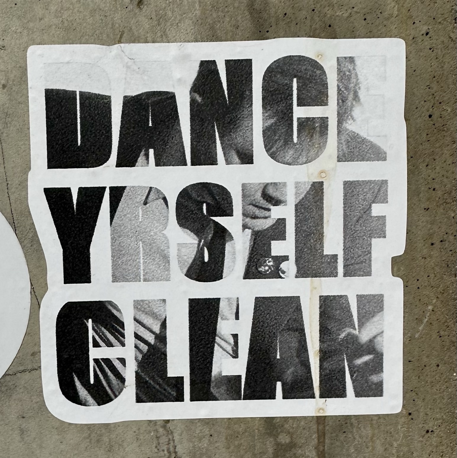 sticker on a wall that reads "Dance Yrself Clean"