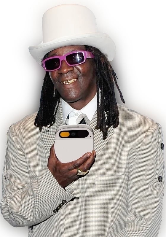 Flavor Flav in a white top hat and checkered suit coat taking procession of his new oversized Humane AI Pin.