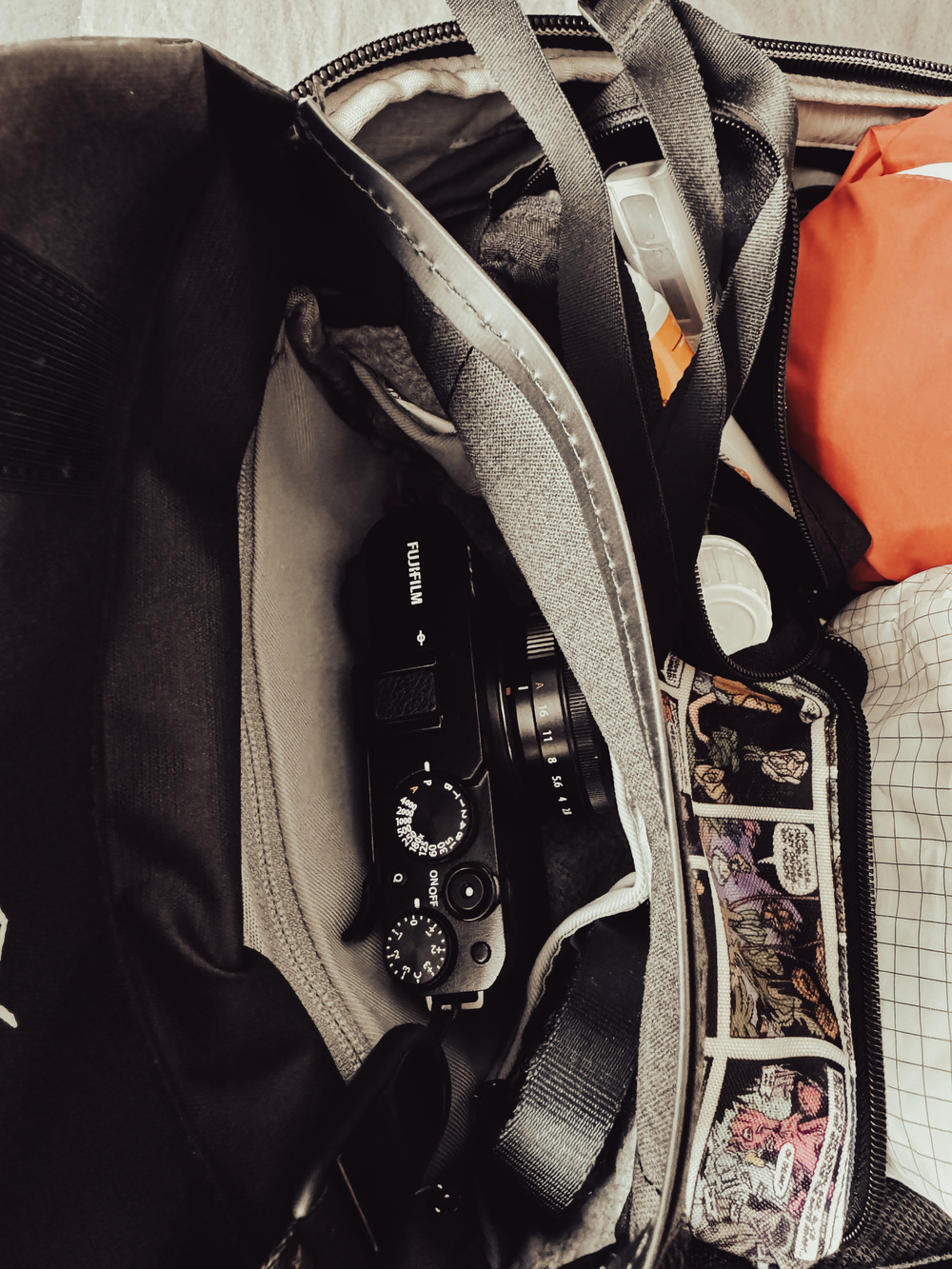 A camera, and various items are inside an open black bag.