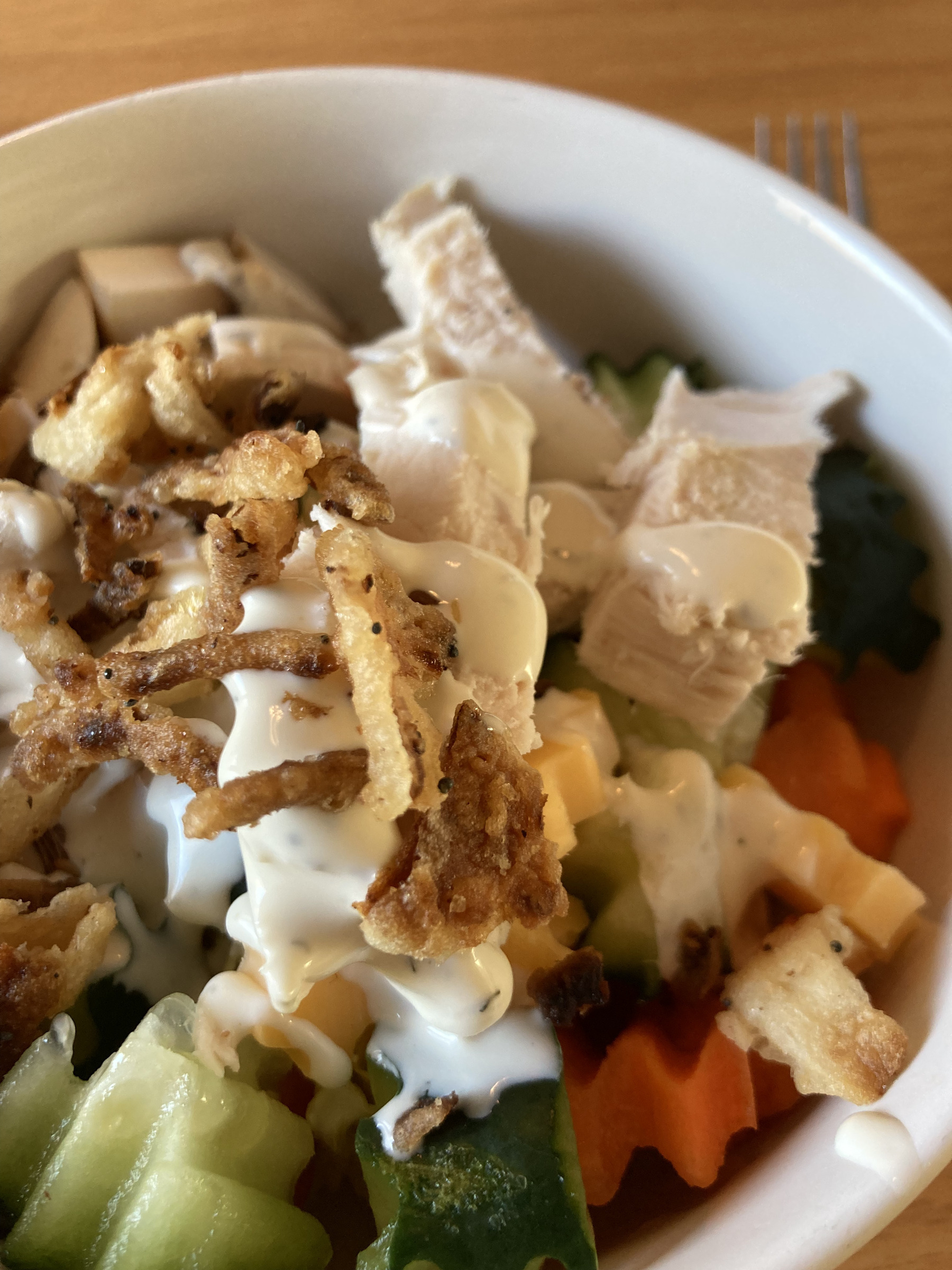 Salad of lettuce, cucumber, carrot, chicken, fried onions, and ranch dressing.