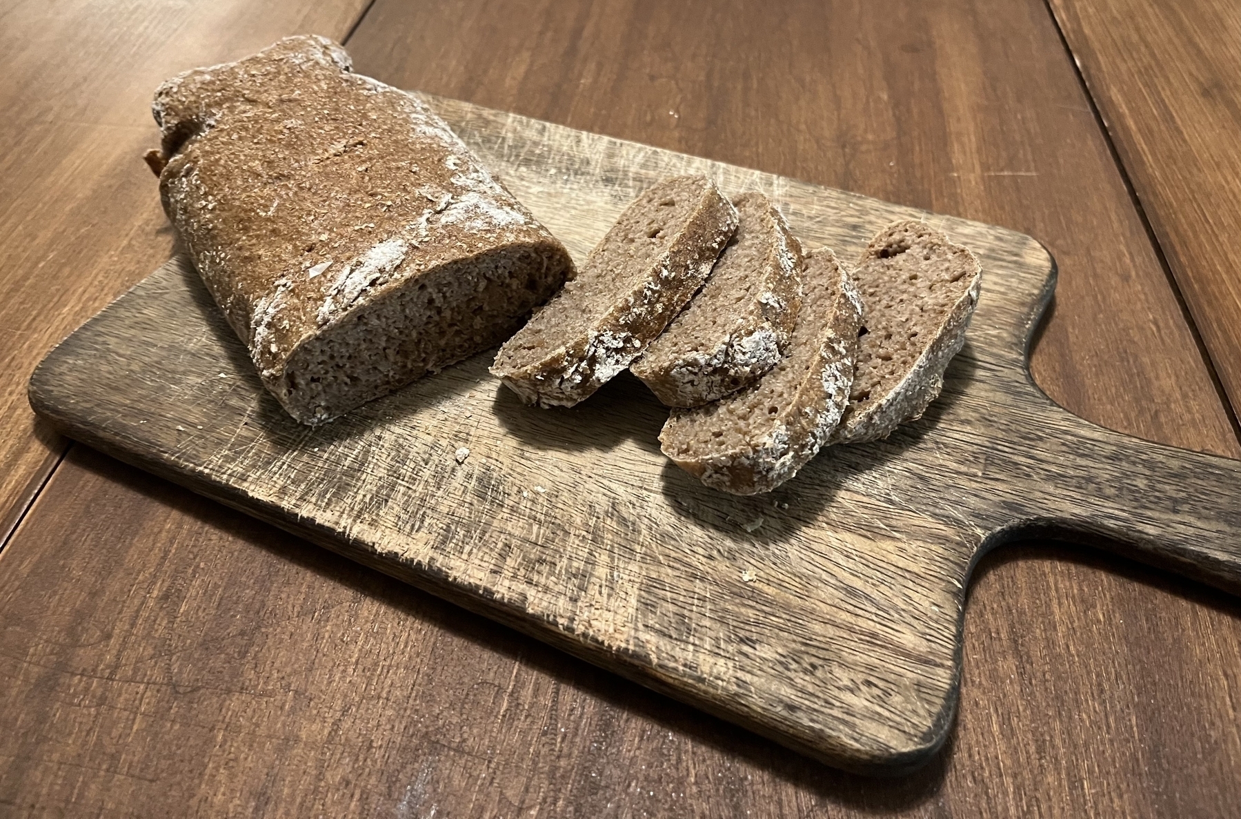 Sliced dark bread sitting on a wooden cutting board