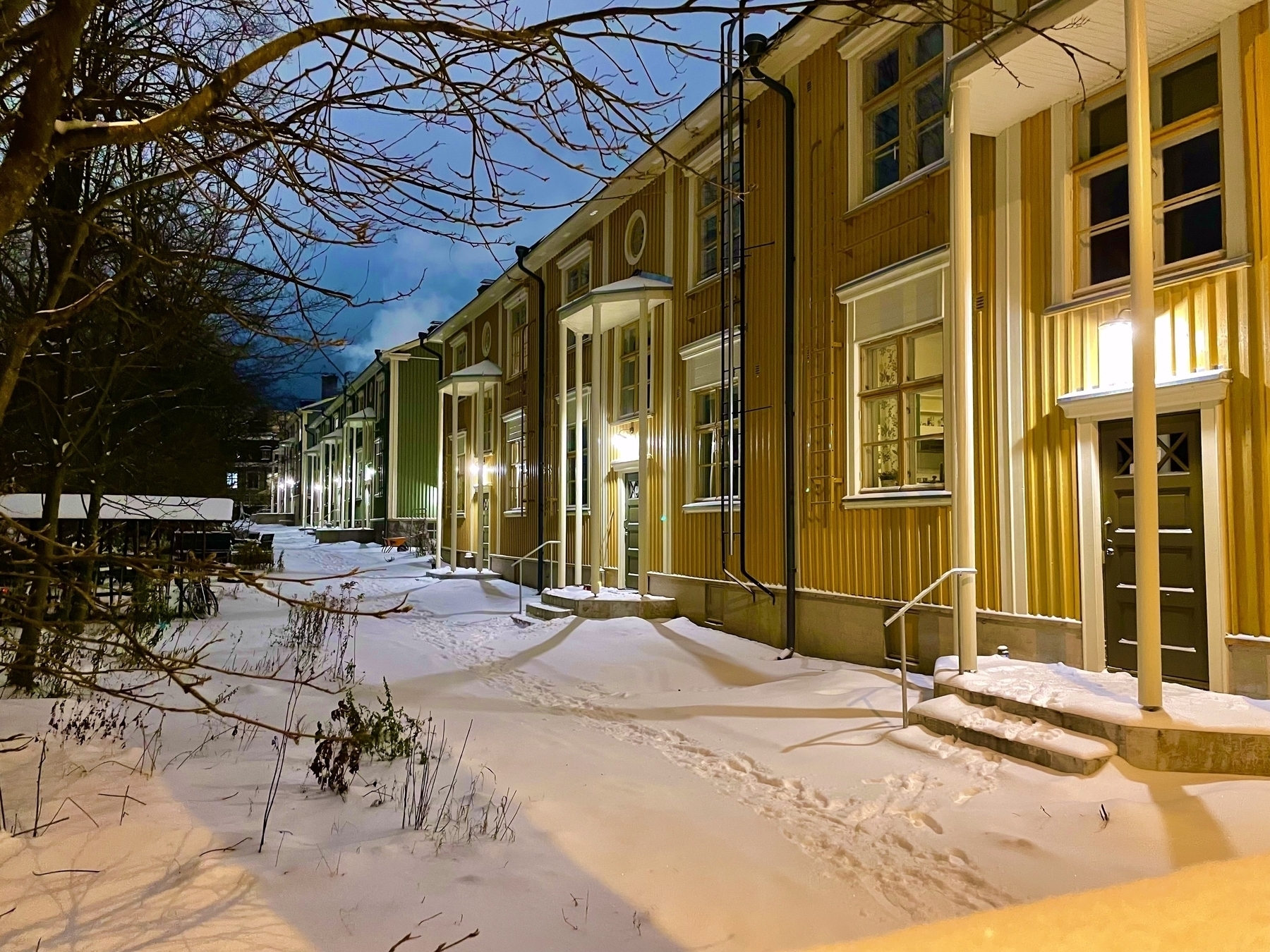 A row of houses in Vallila, Helsinki, with entrances with big pillars, evening photo with snow on the ground