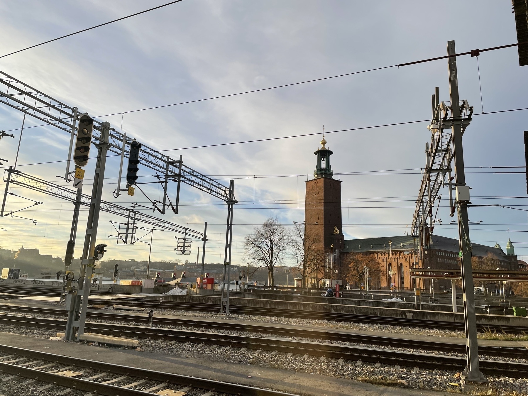 A view of Stockholm city hall on a clear morning.  There are rail tracks in the foreground. 