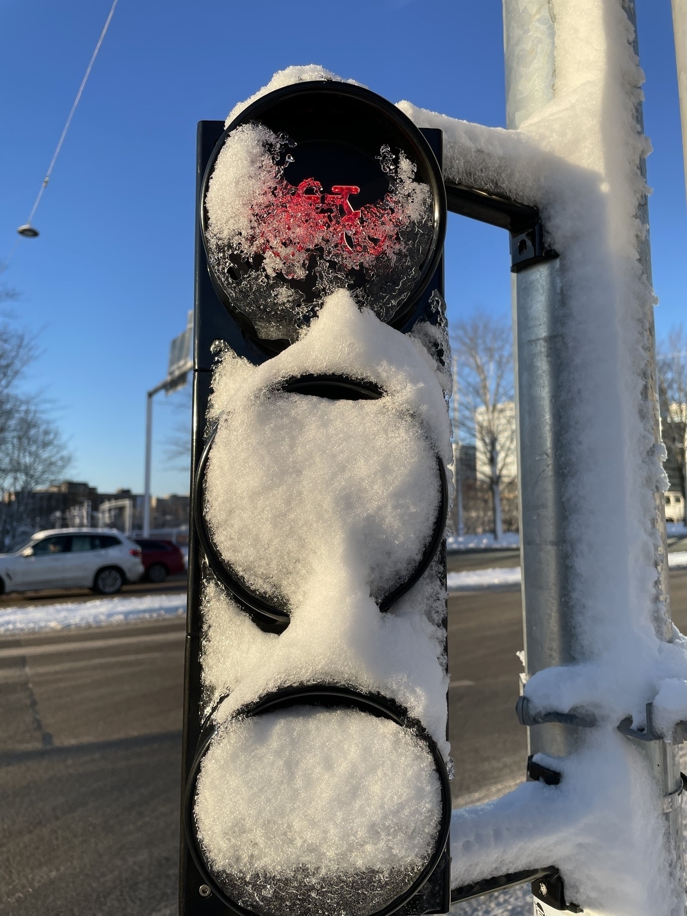 Traffic light covered in snow. Red signal is visible behind ice and snow. 