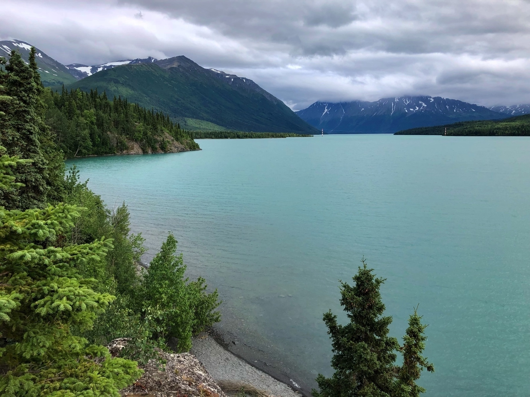 Bay of light blue water meets a forested ridge