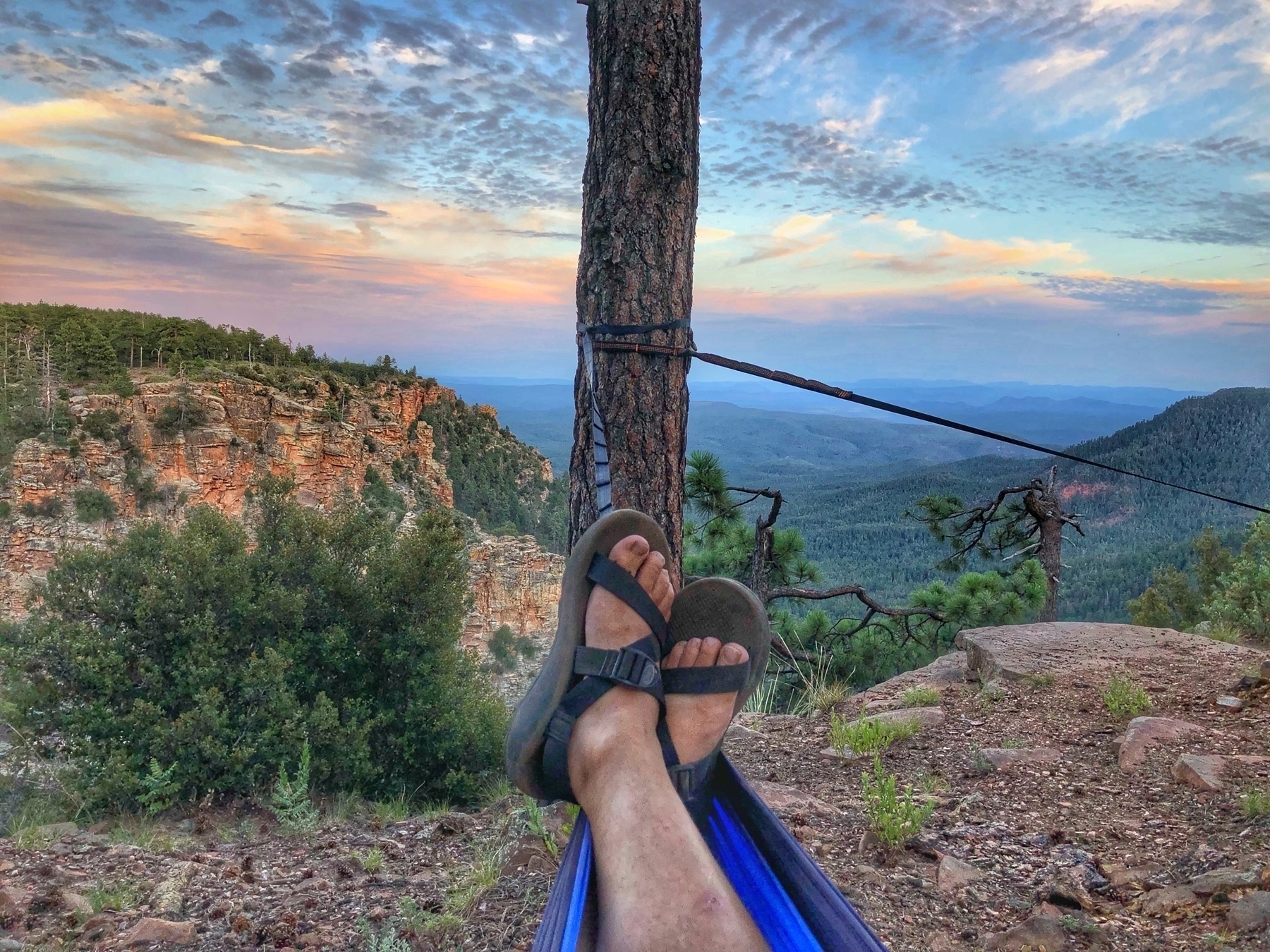 View from the feet of someone lounging in a hammock near the edge of a cliff and a great vista 