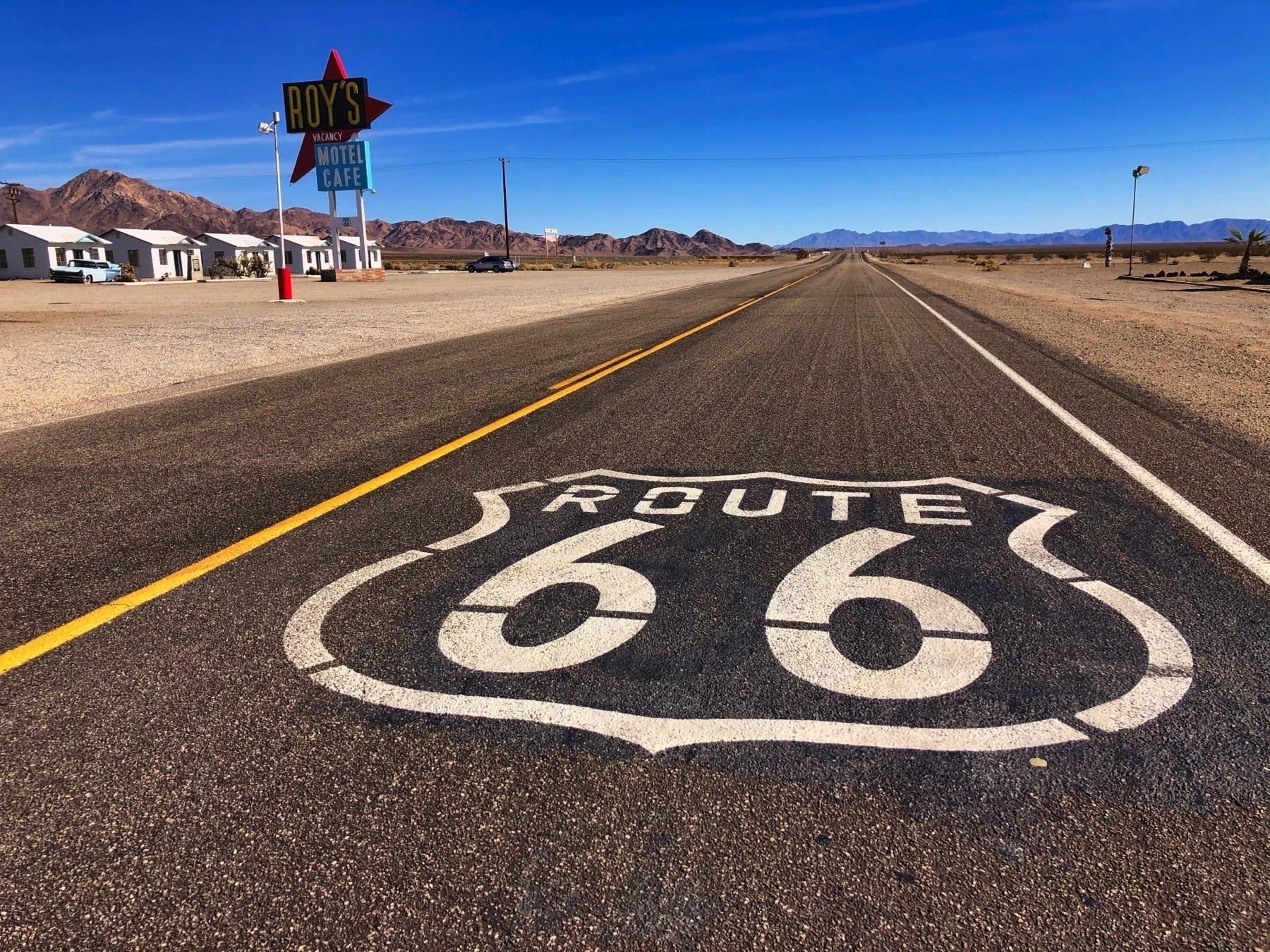 Route 66 painted on a lonely highway with Roy’s Cafe in the background, a classic RT66 diner near Amboy, CA