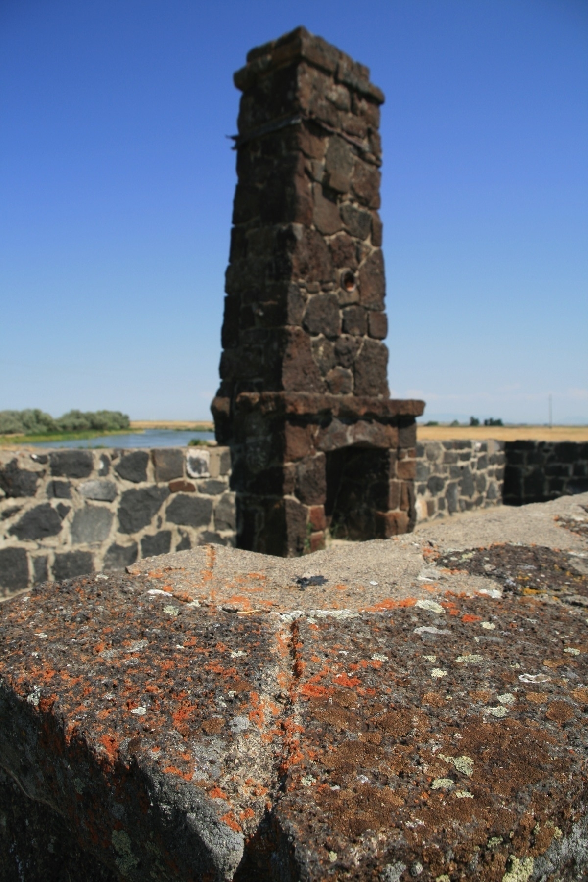 Ruins of a stone fireplace, surrounded by a low wall