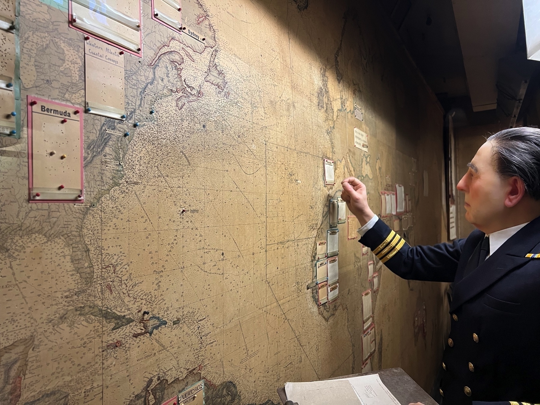 A manican adding a push pin to a wall map in a darkened room.