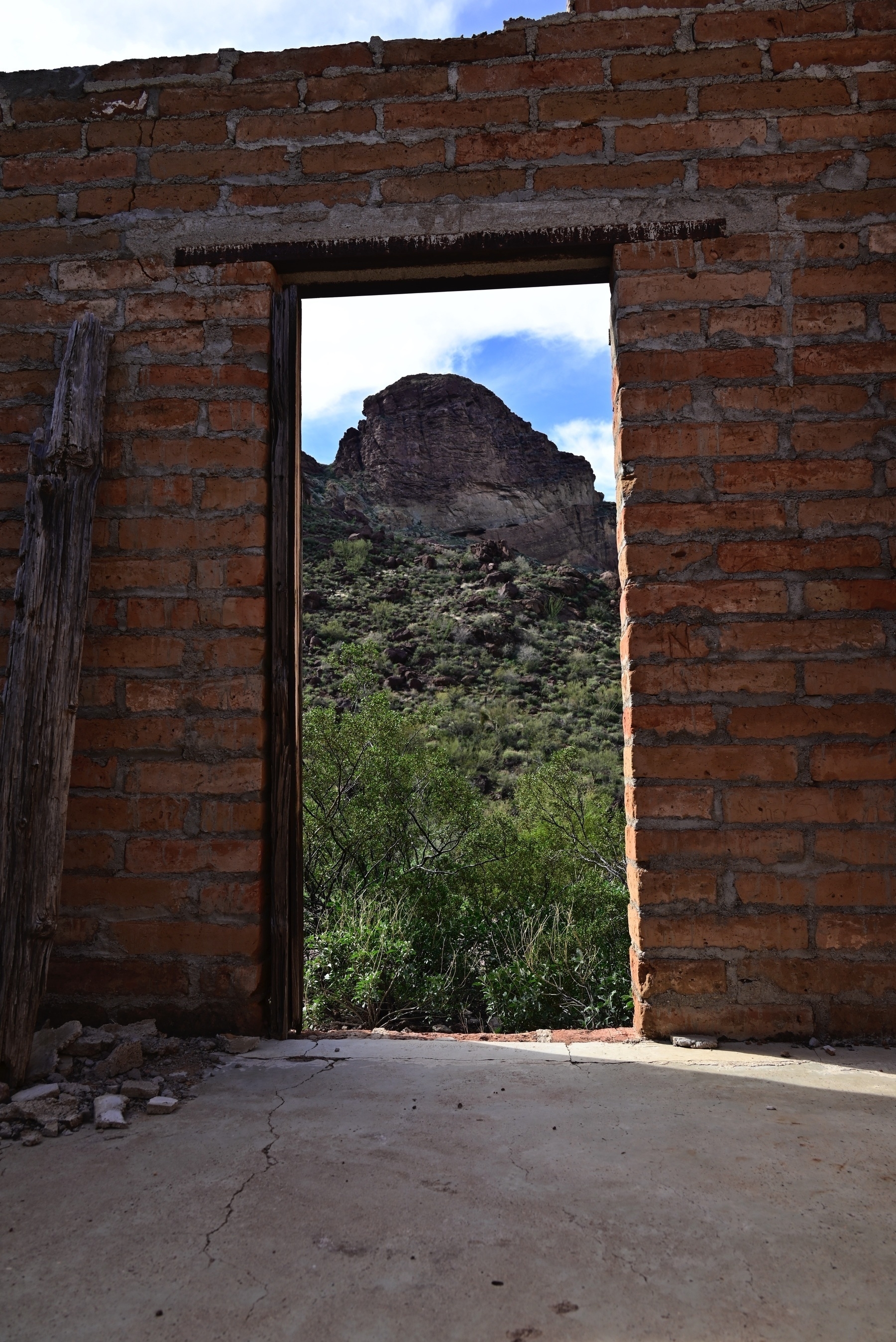 Desert peak as seen through an open doorway in a roofless brick structure