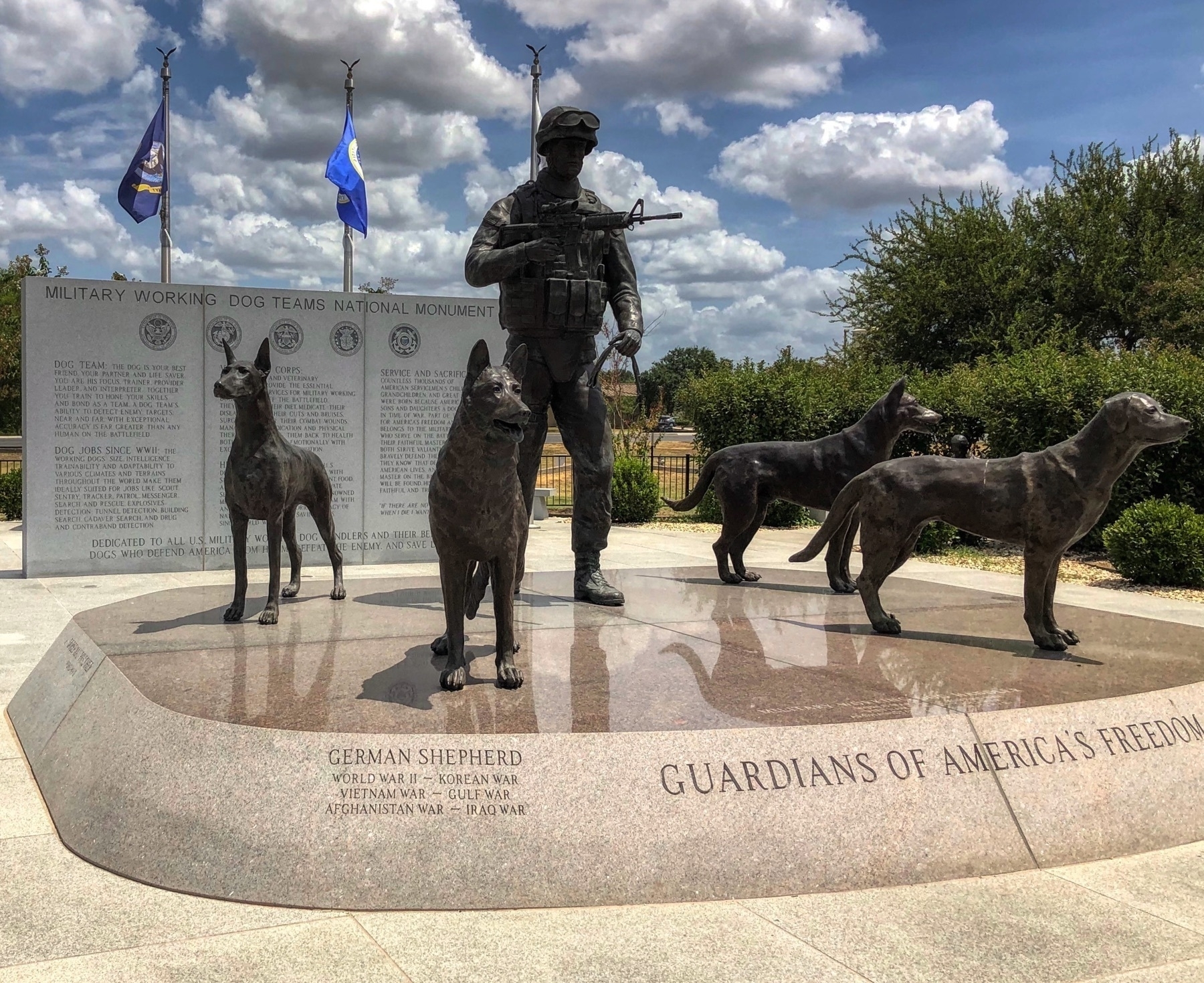 A statue of a soldier, surrounded by four dogs.