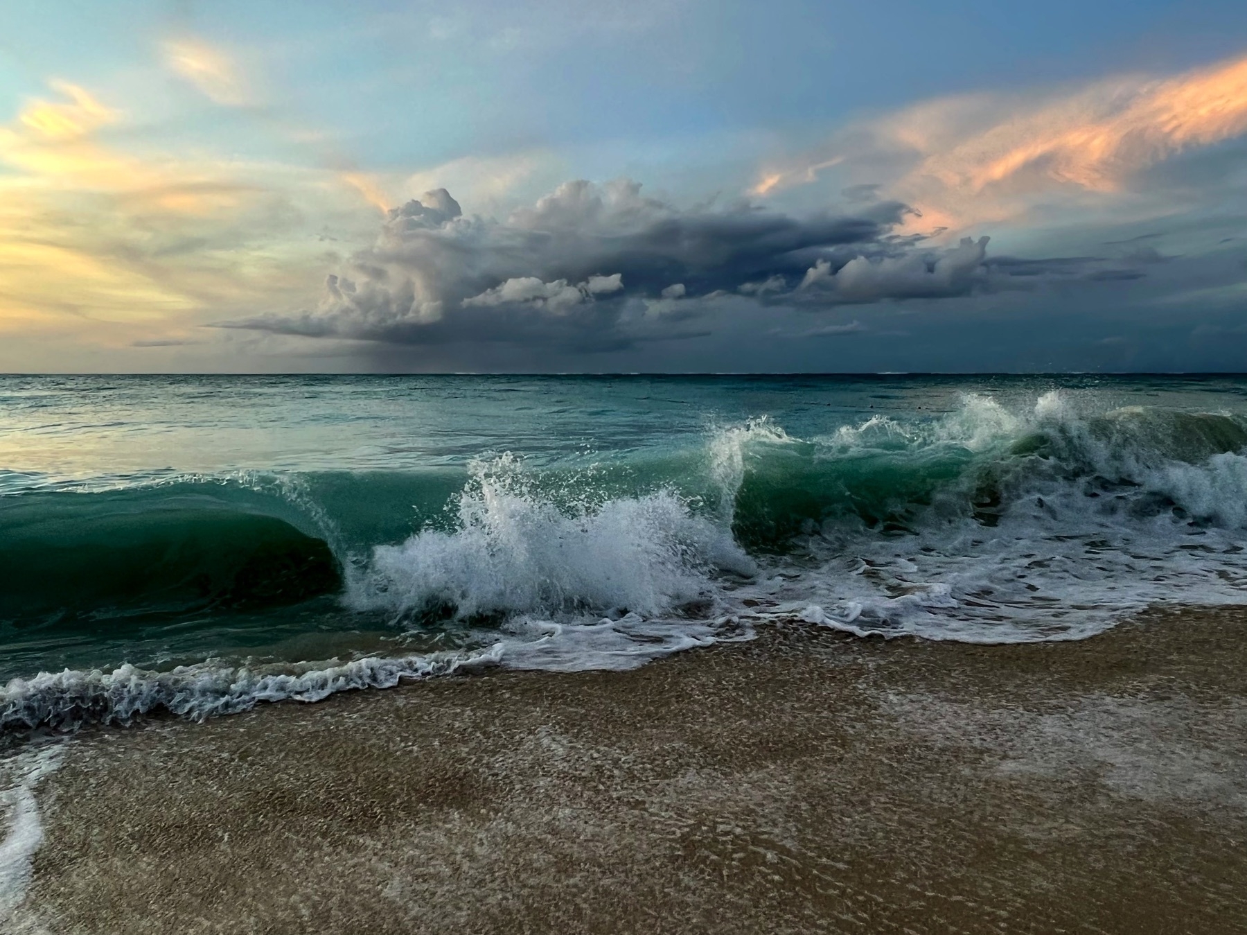 Wave crashing in with storn cloud in the distance