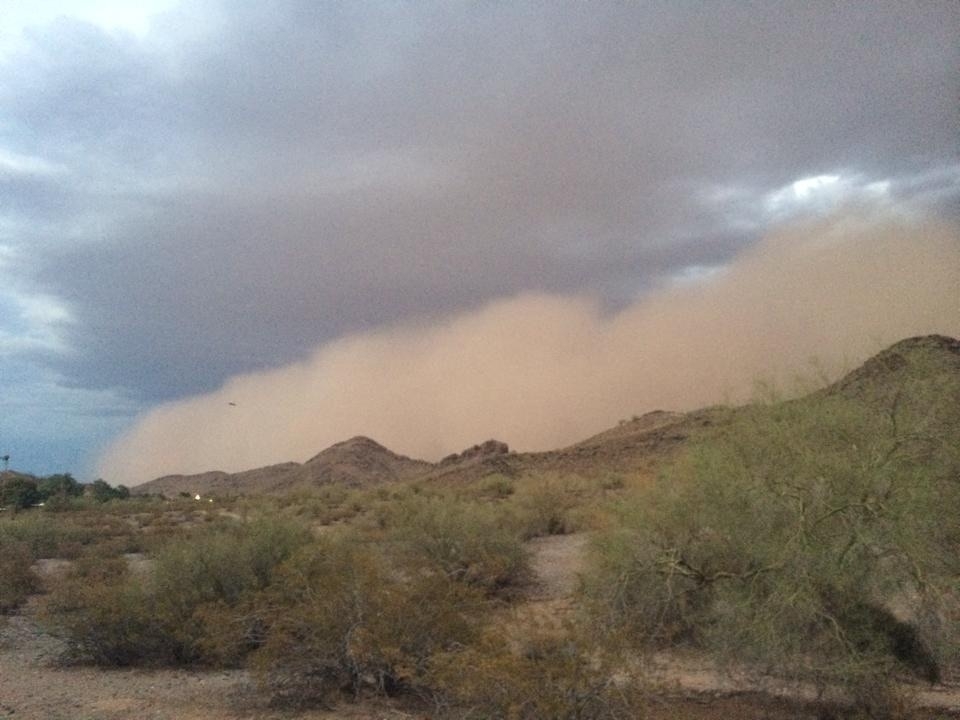 Big ass dust storm with well defined edge cresting a desert hillside 