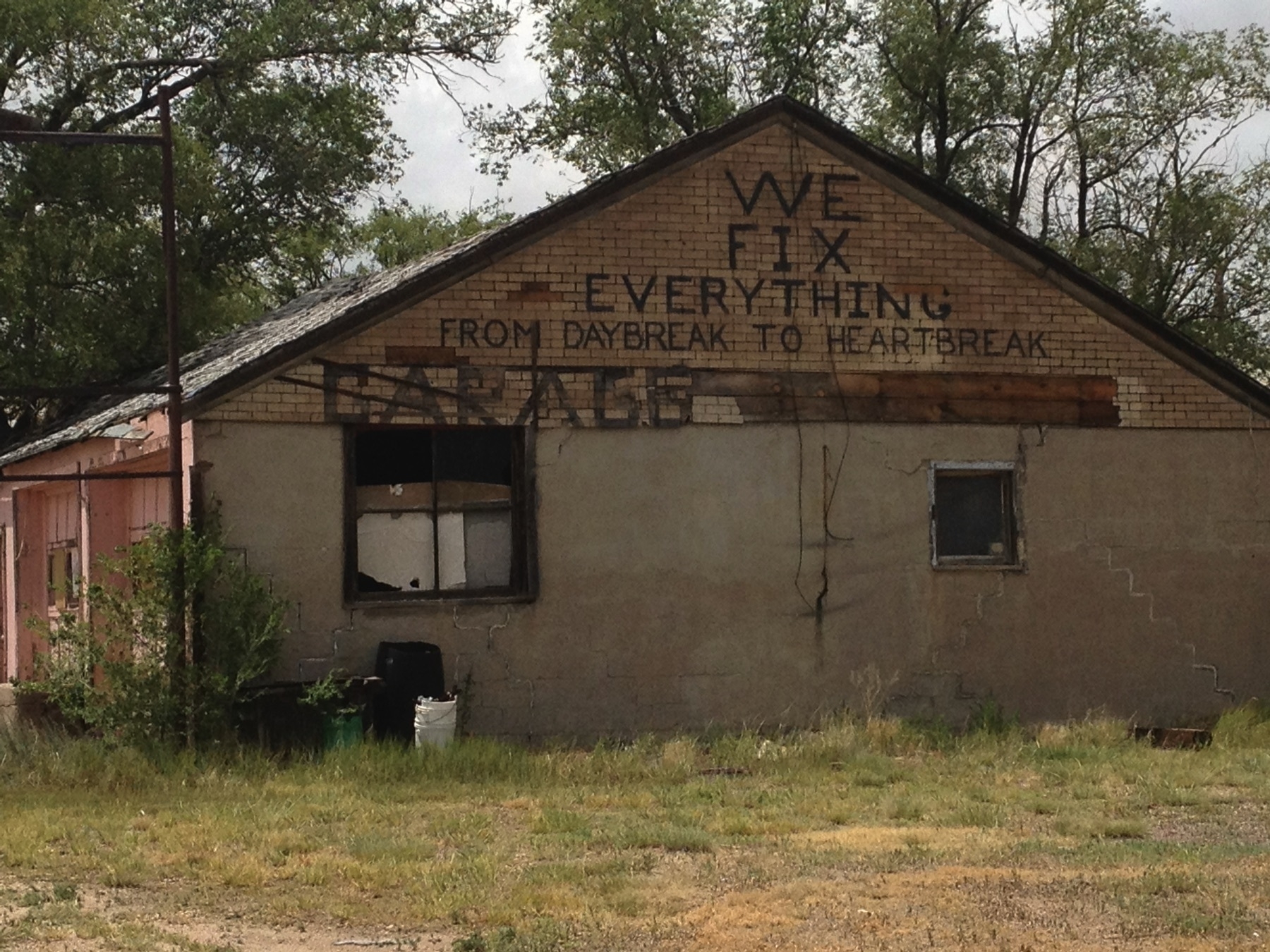 Rundown building with painted sign that reads “We fix everything from daybreak to heartbreak”