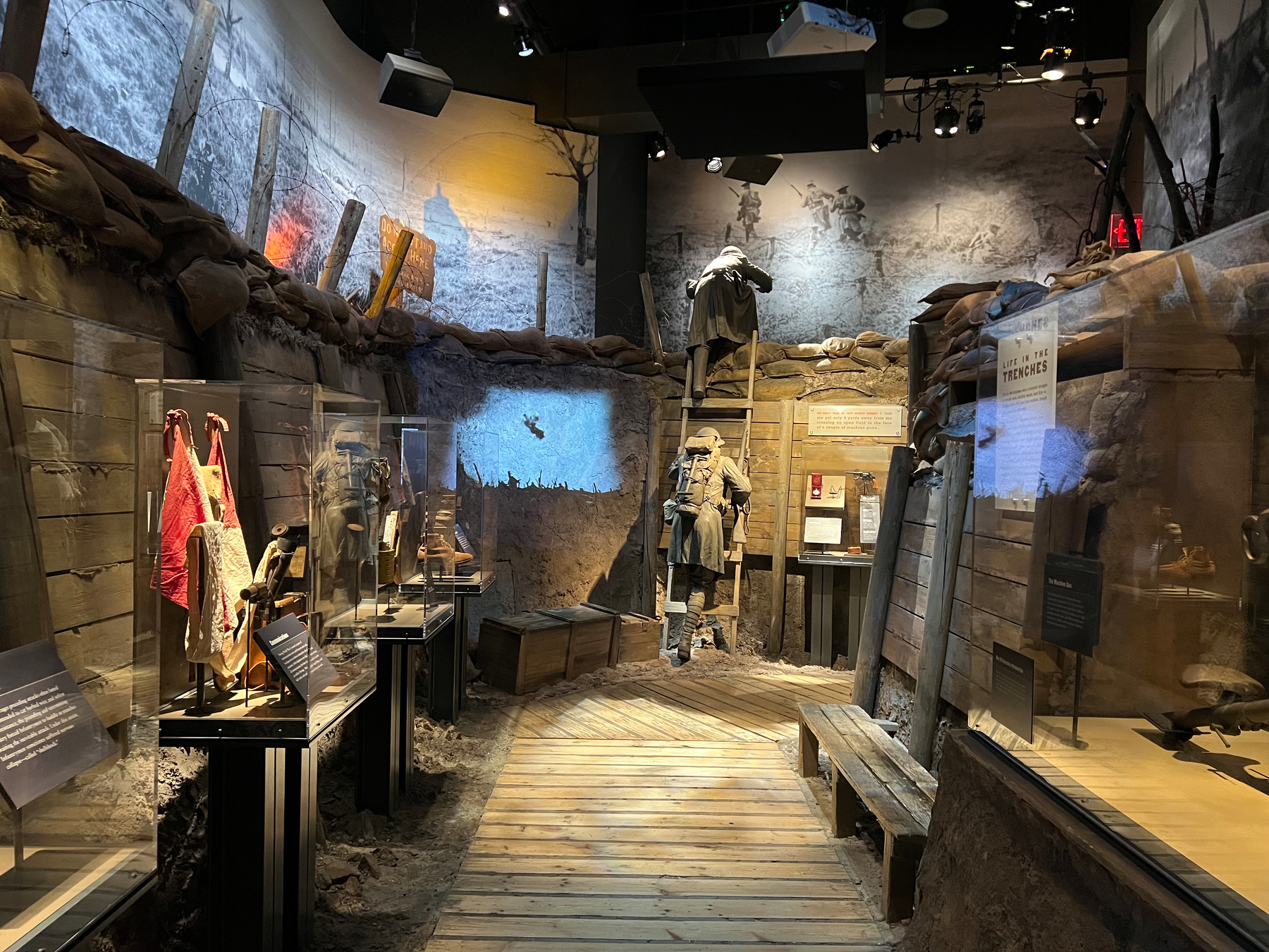 A museum exhibit depicts a World War I trench scene with artifacts and displays along the walls.