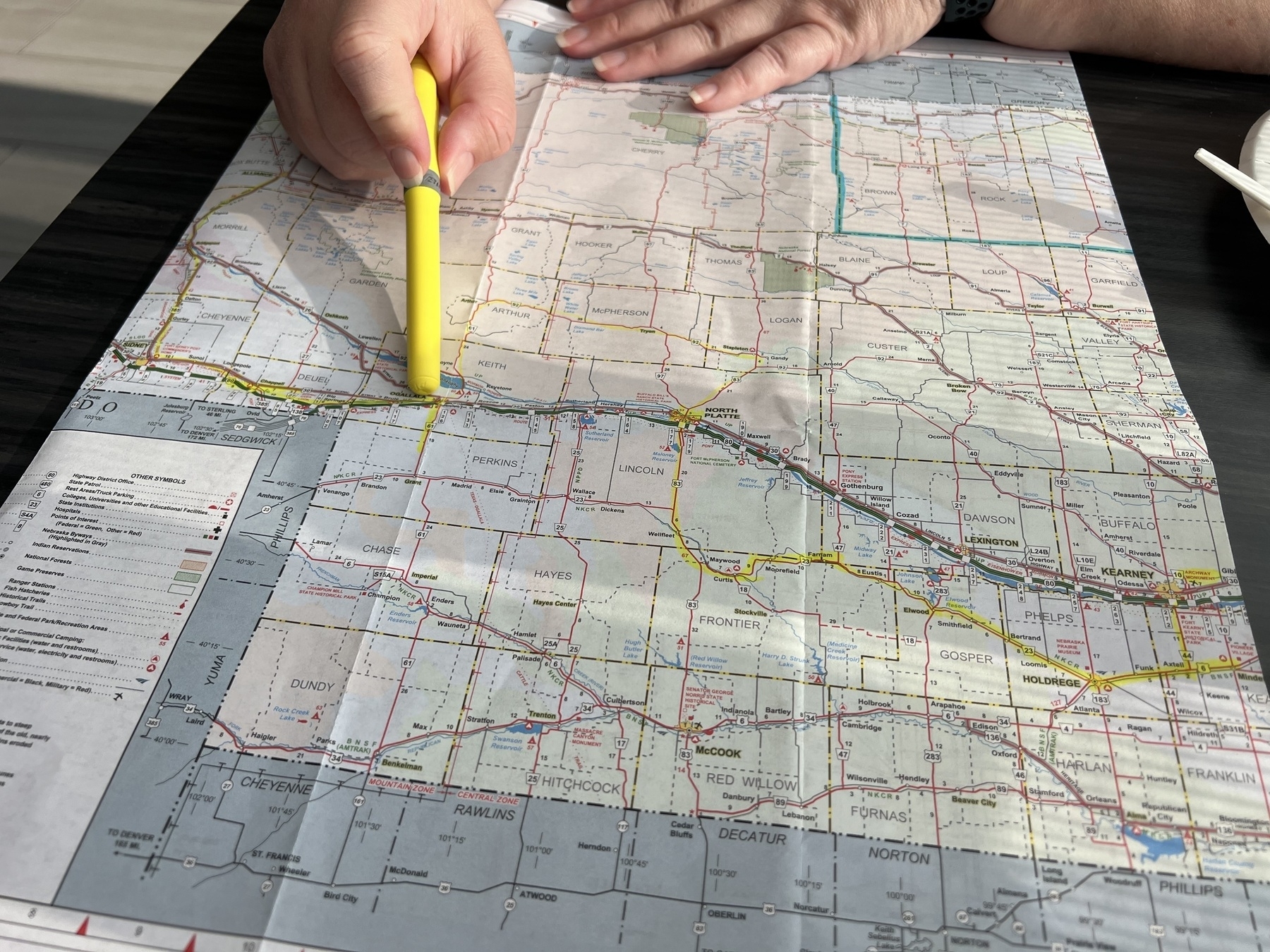 A person is pointing at a road map with a yellow highlighter.