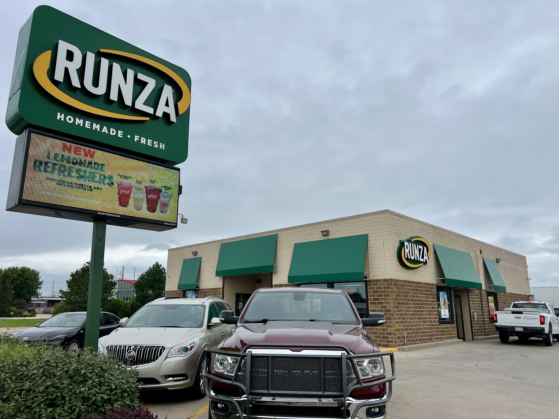 A Runza restaurant with a prominent sign and several parked cars in front.